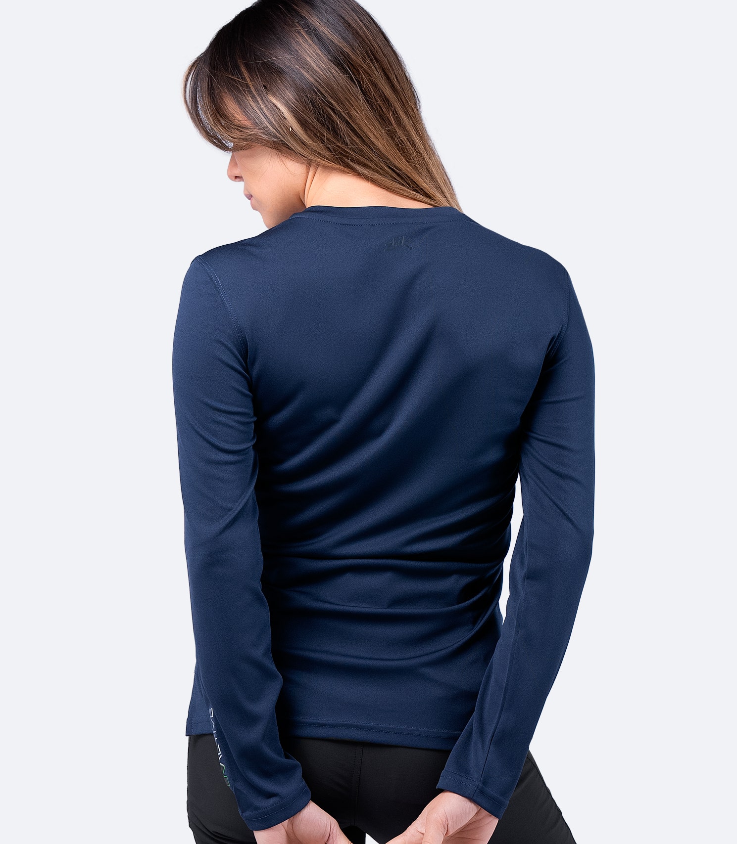 Vista posterior de la camiseta de manga larga UVActive Zhik para mujer en color Navy, que muestra un ajuste cónico, tejido duradero y tecnología de absorción de la humedad.