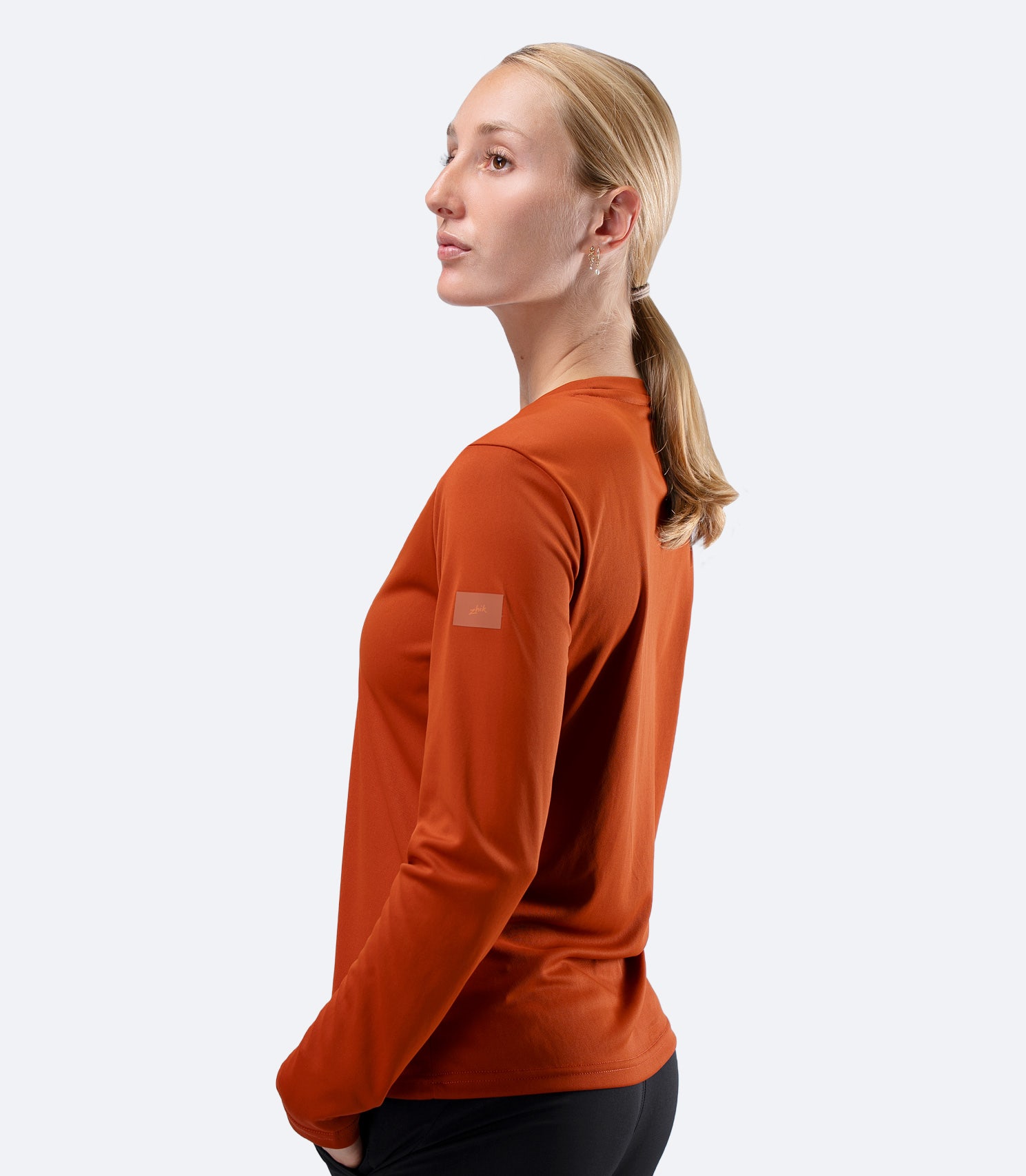 Side shoulder view of Women's Zhik UVActive tech top in Red Earth, highlighting clean fit and breathable fabric