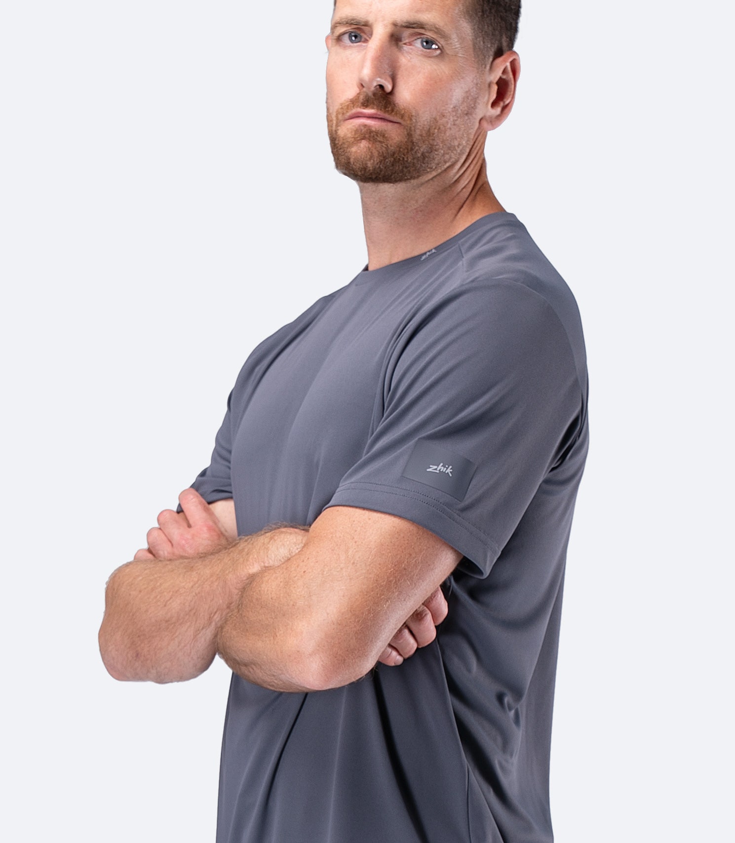 Side profile of Zhik Men's UVActive Short Sleeve Tech Tee in Slate with arms crossed, sporty outline