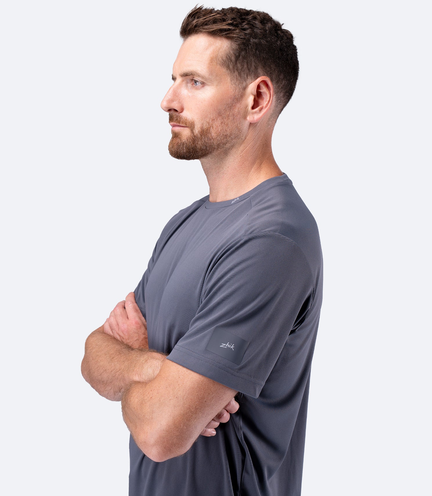 Side profile of Zhik Men's UVActive Short Sleeve Tech Tee in Slate with arms crossed, sporty outline