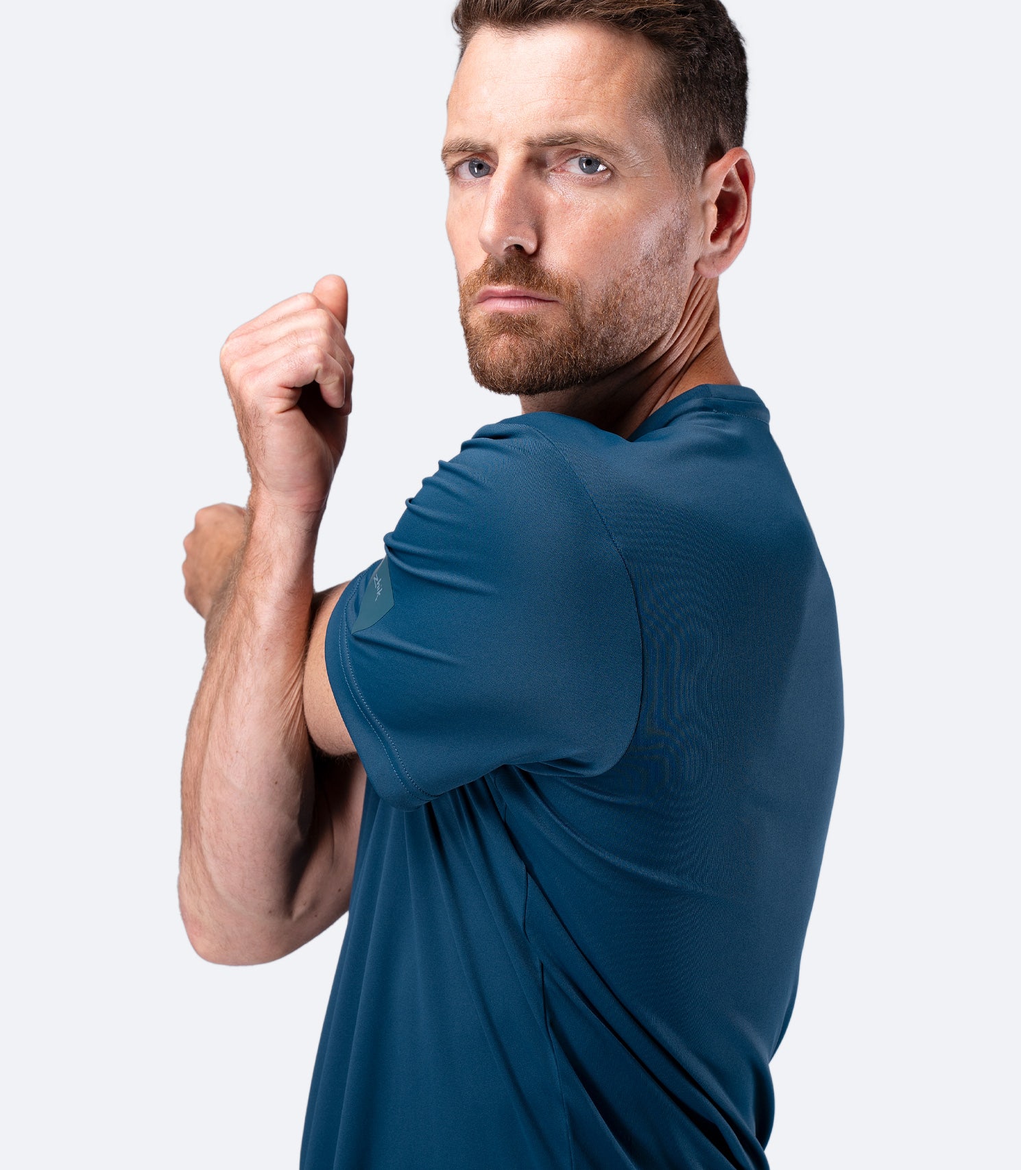Close-up side view of Zhik Men's UVActive Tee in Deep Teal with arms stretching to show shoulder mobility