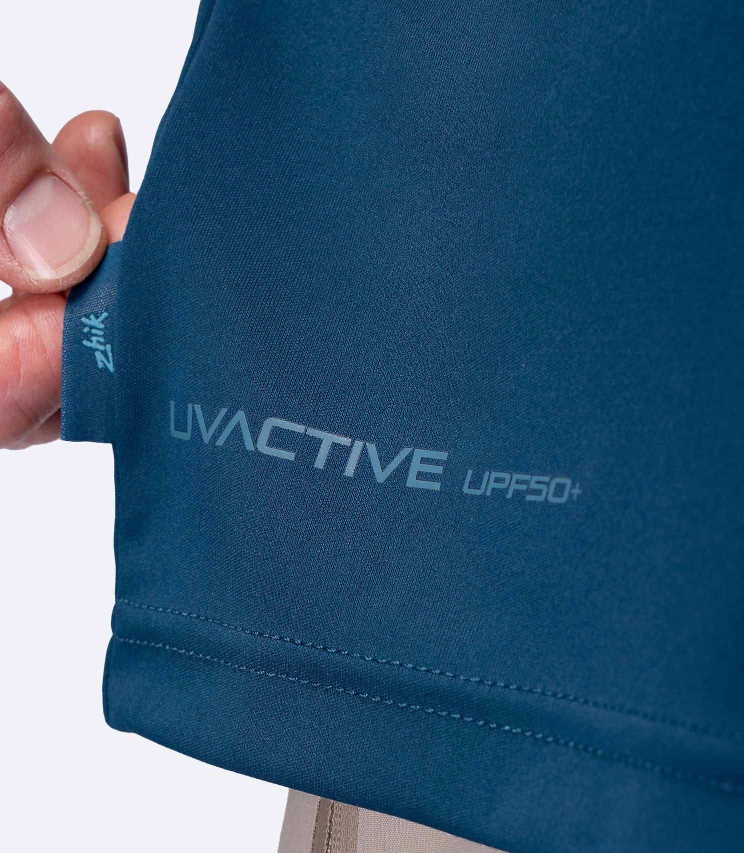 Close-up of UVACTIVE UPF 50+ logo and subtle Zhik tag at waist on Deep Teal Men's Tech Tee