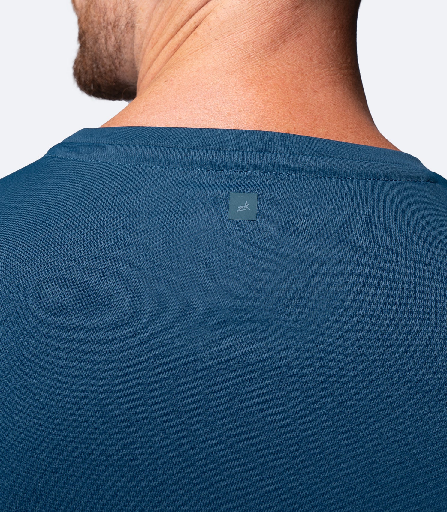Back shoulder blade close-up of Zhik Men's UVActive Tech Tee in Deep Teal with small rear logo