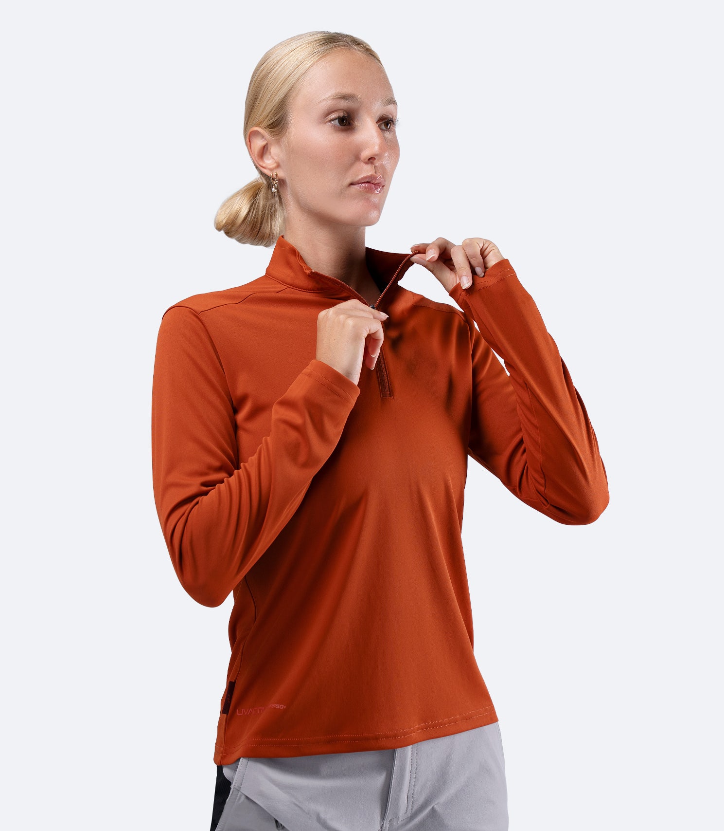 Front view of Red Earth Zhik Women's UVActive 1/4 Zip Top, hand on zip for venting and thermal control