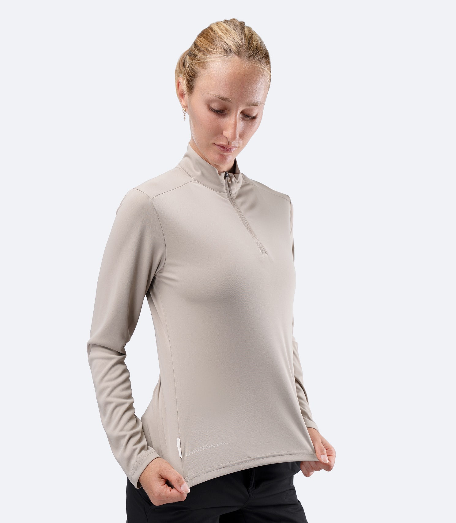 Front profile of Stone Zhik Women's UVActive Tech Top, hand on waist stretching hem fabric