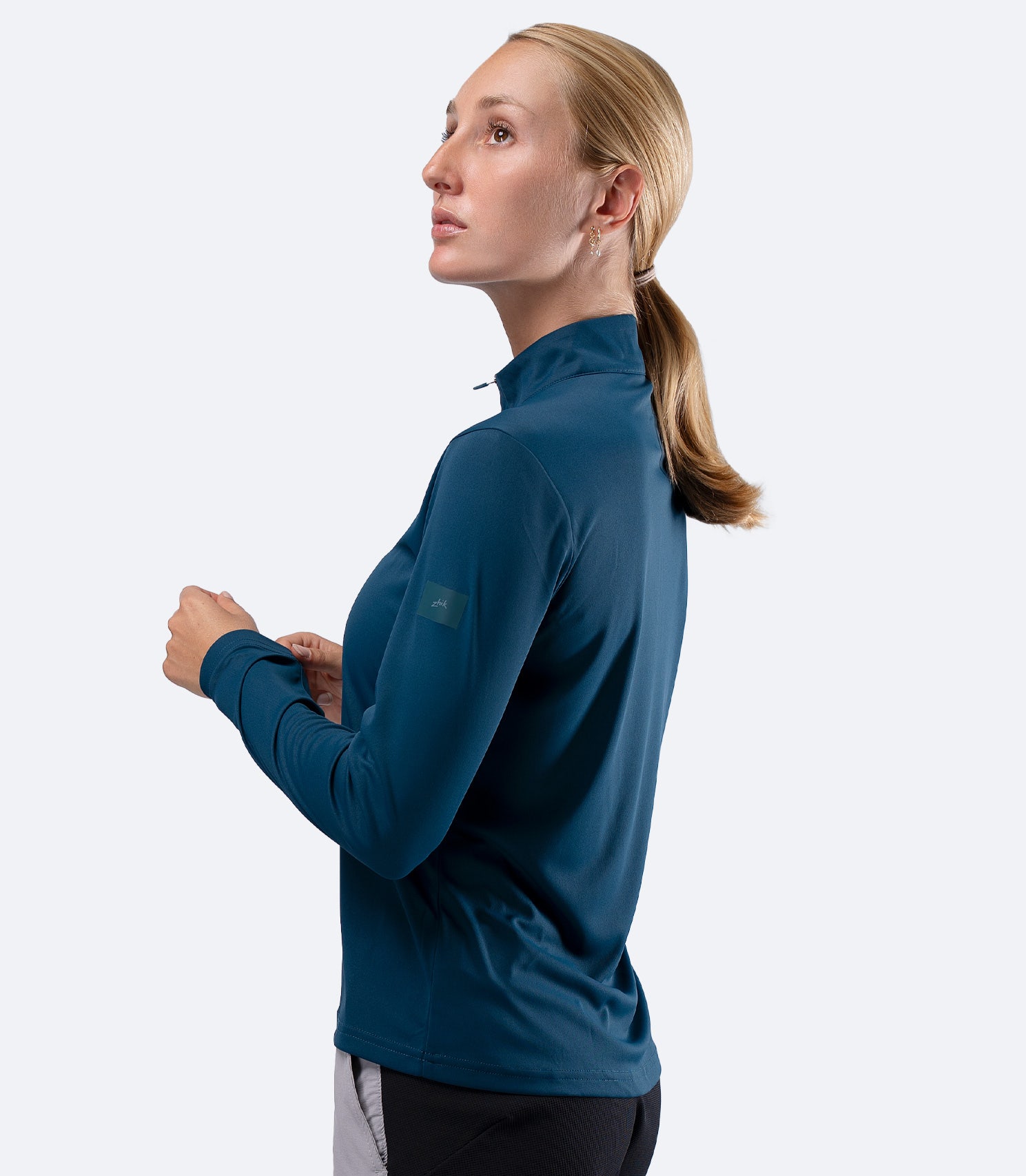 Side profile of Zhik Women's UVActive 1/4 Zip Long Sleeve Tech Top in Deep Teal, showing regular fit