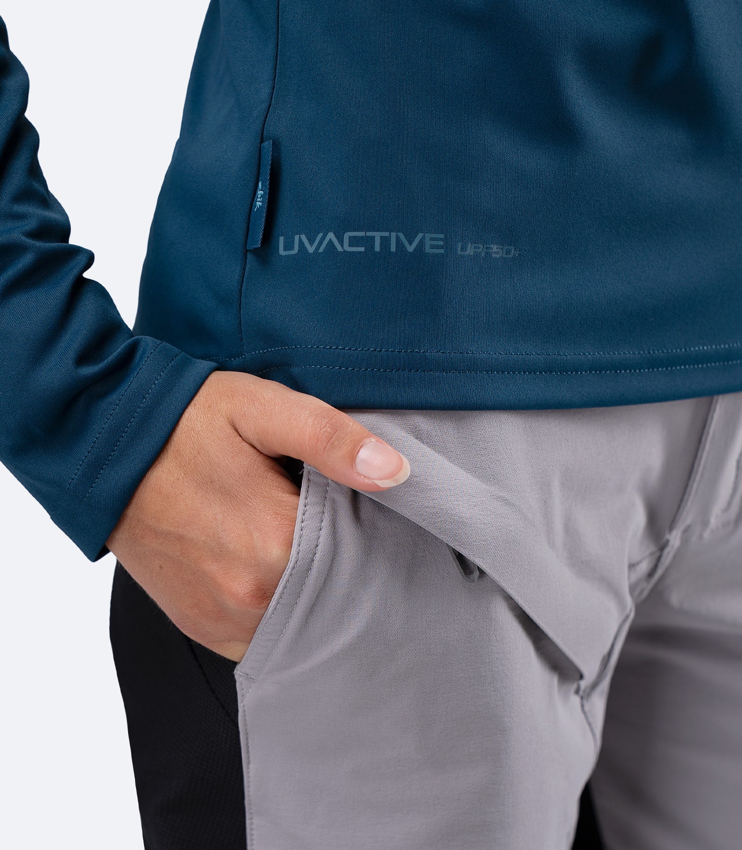 Close-up of UVActive UPF50+ logo and subtle Zhik tag at waistline on Deep Teal Women's Tech Top