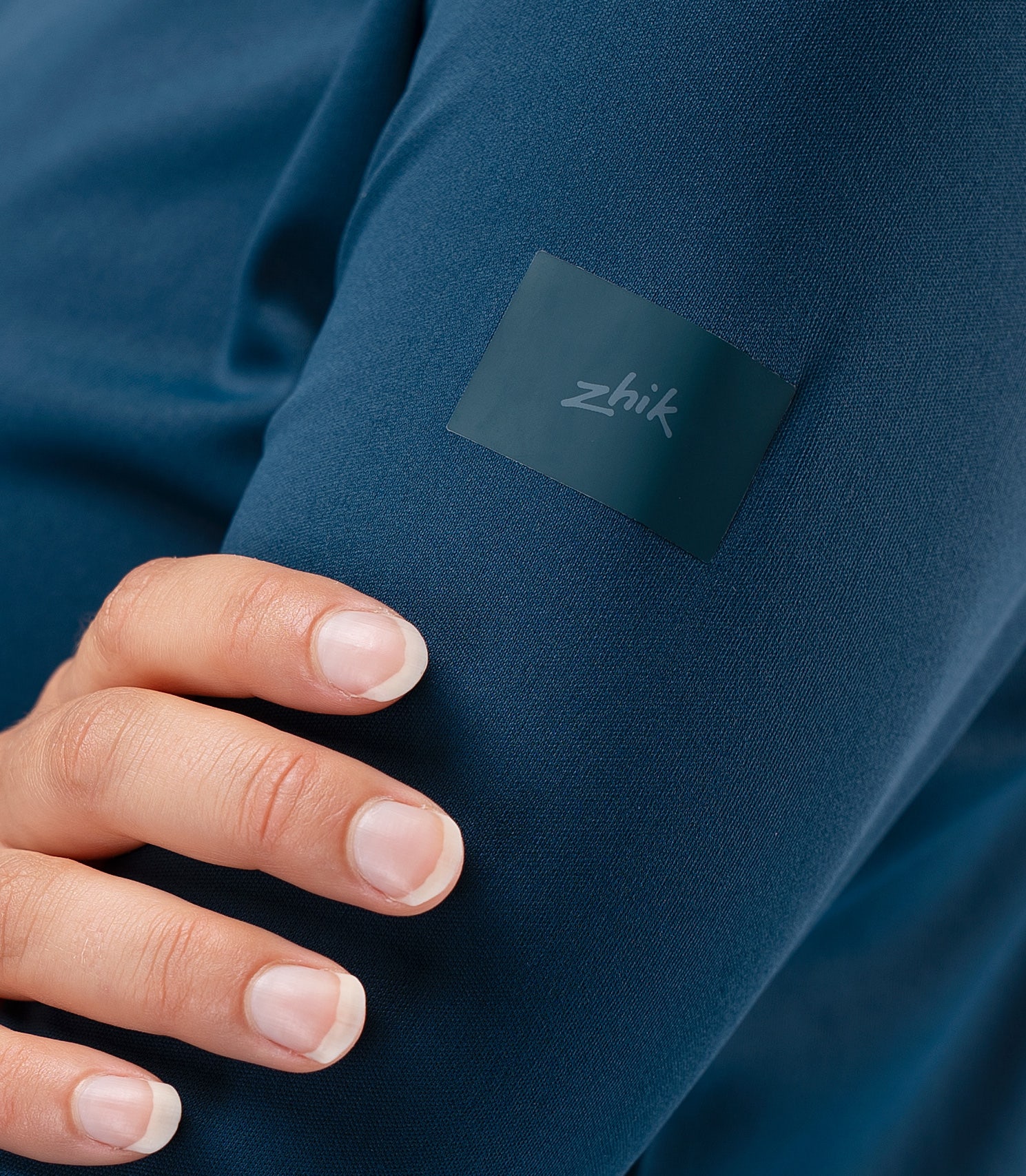 Close-up of subtle Zhik logo on shoulder of Women's UVActive 1/4 Zip Top in Deep Teal