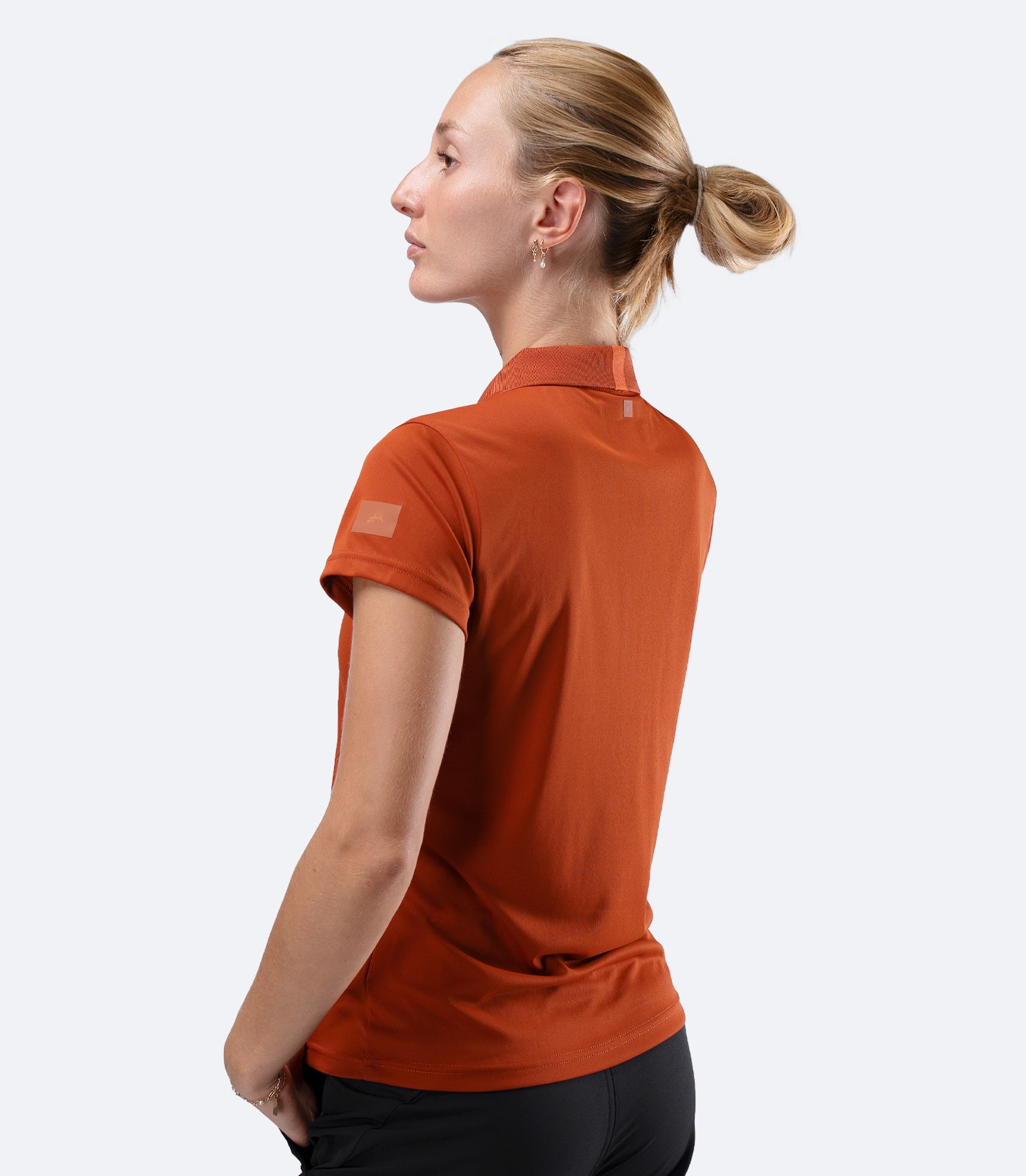 Side profile of Zhik UVActive Polo in Red Earth with arms crossed, showing smooth, snag-resistant fabric