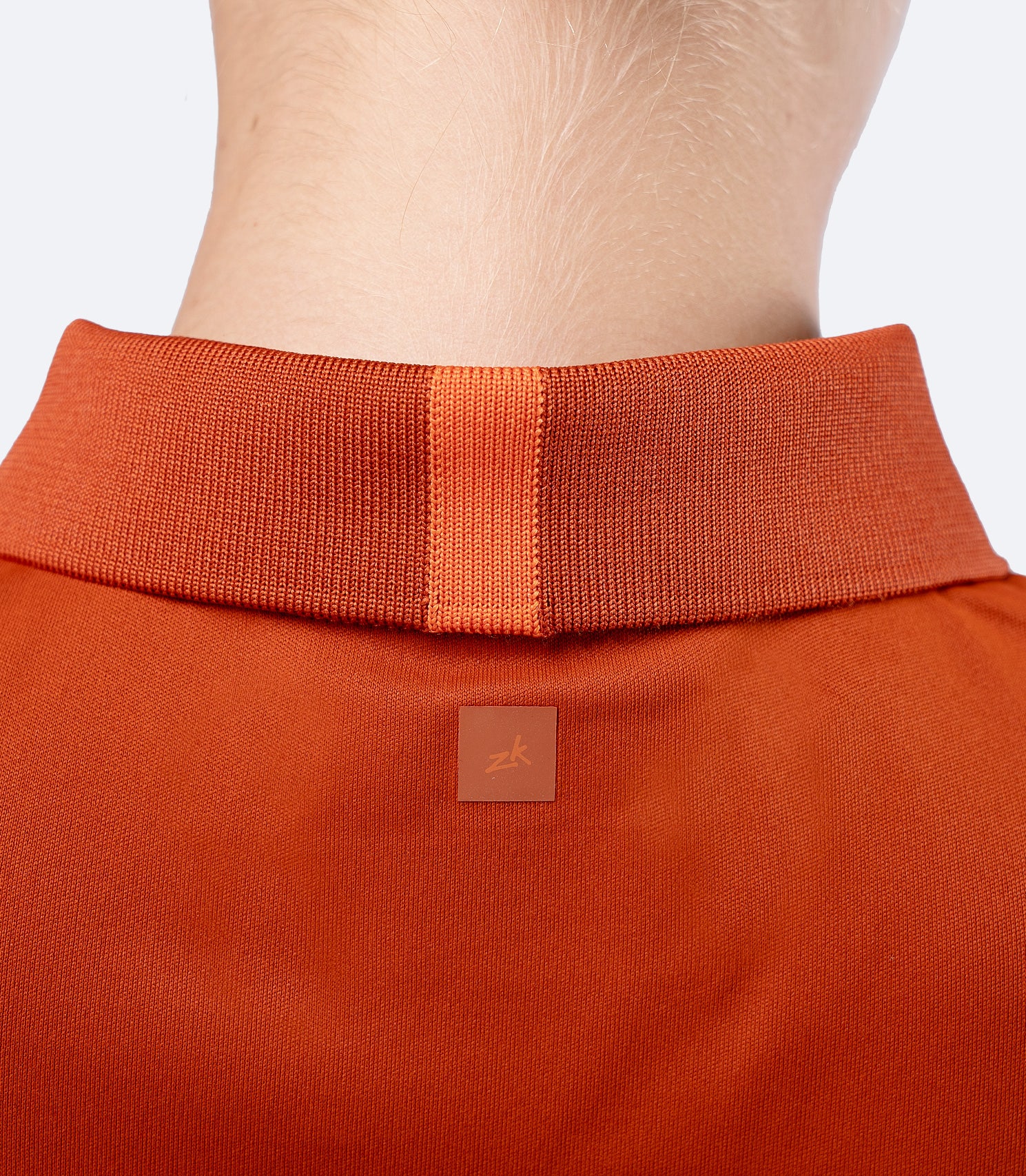 Close-up of below neck on Zhik UVActive Polo in Red Earth, subtle back logo and smooth high-gauge knit