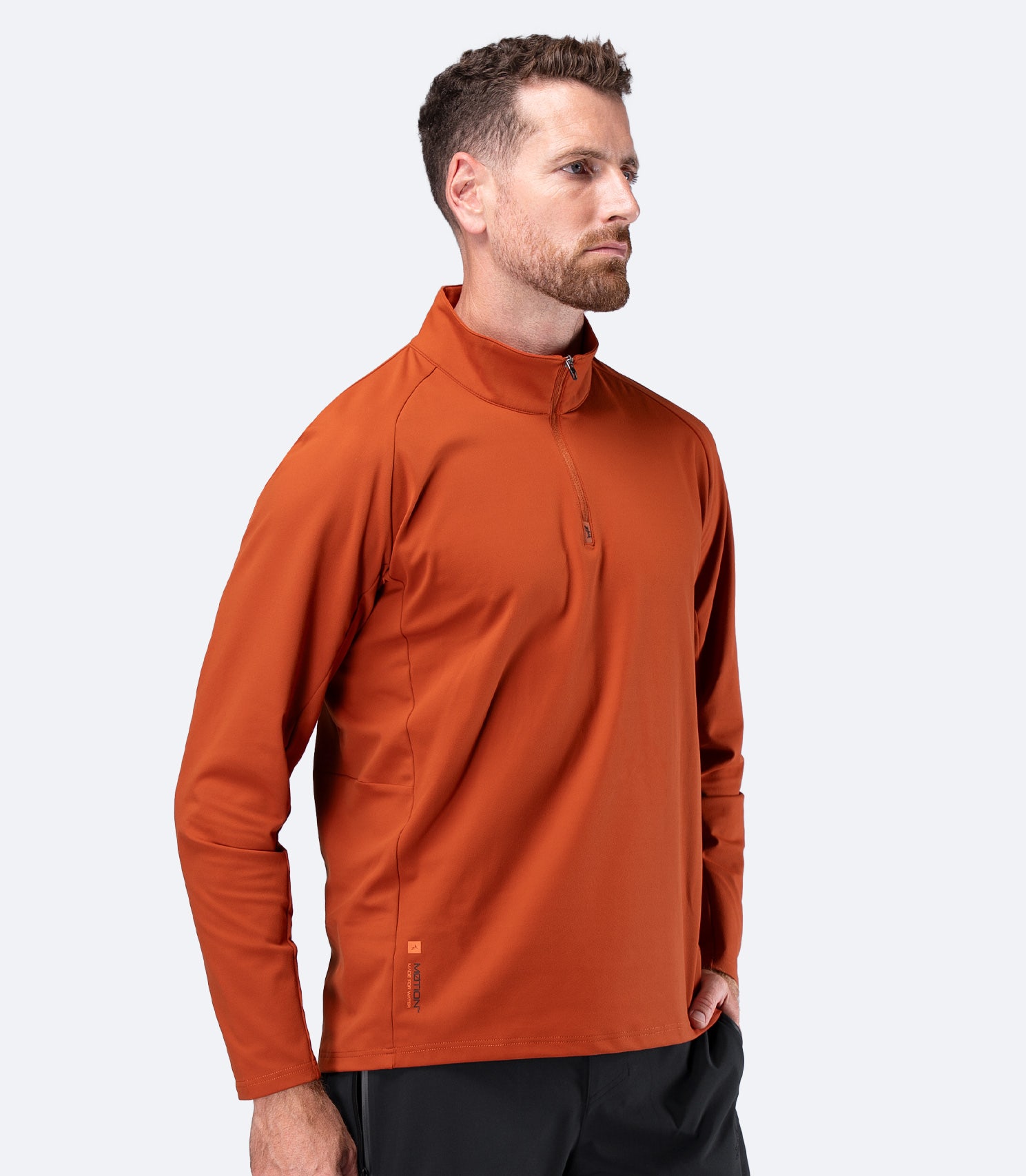 Side view of Zhik Men's ZhikMotion 1/4 Zip Long Sleeve Top in Red Earth, showing athletic performance fit