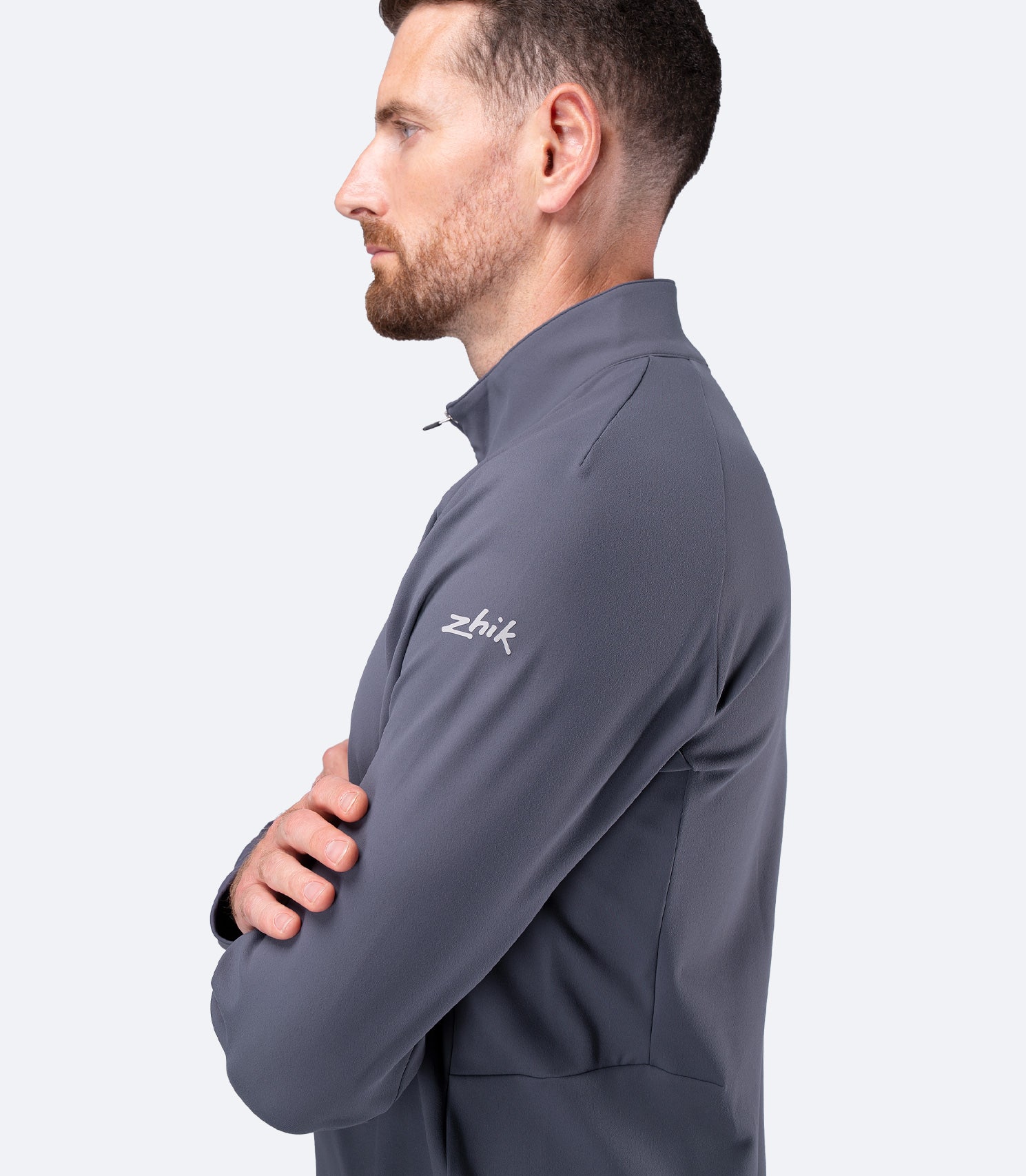 Side profile of Zhik Men's ZhikMotion 1/4 Zip Top in Slate, arms crossed showing flexible stretch fabric