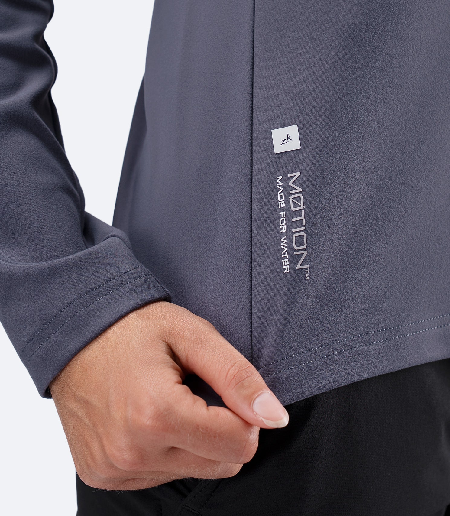 Close up of MOTION Made For Water logo and subtle Zhik branding at waist on ZhikMotion top in Slate