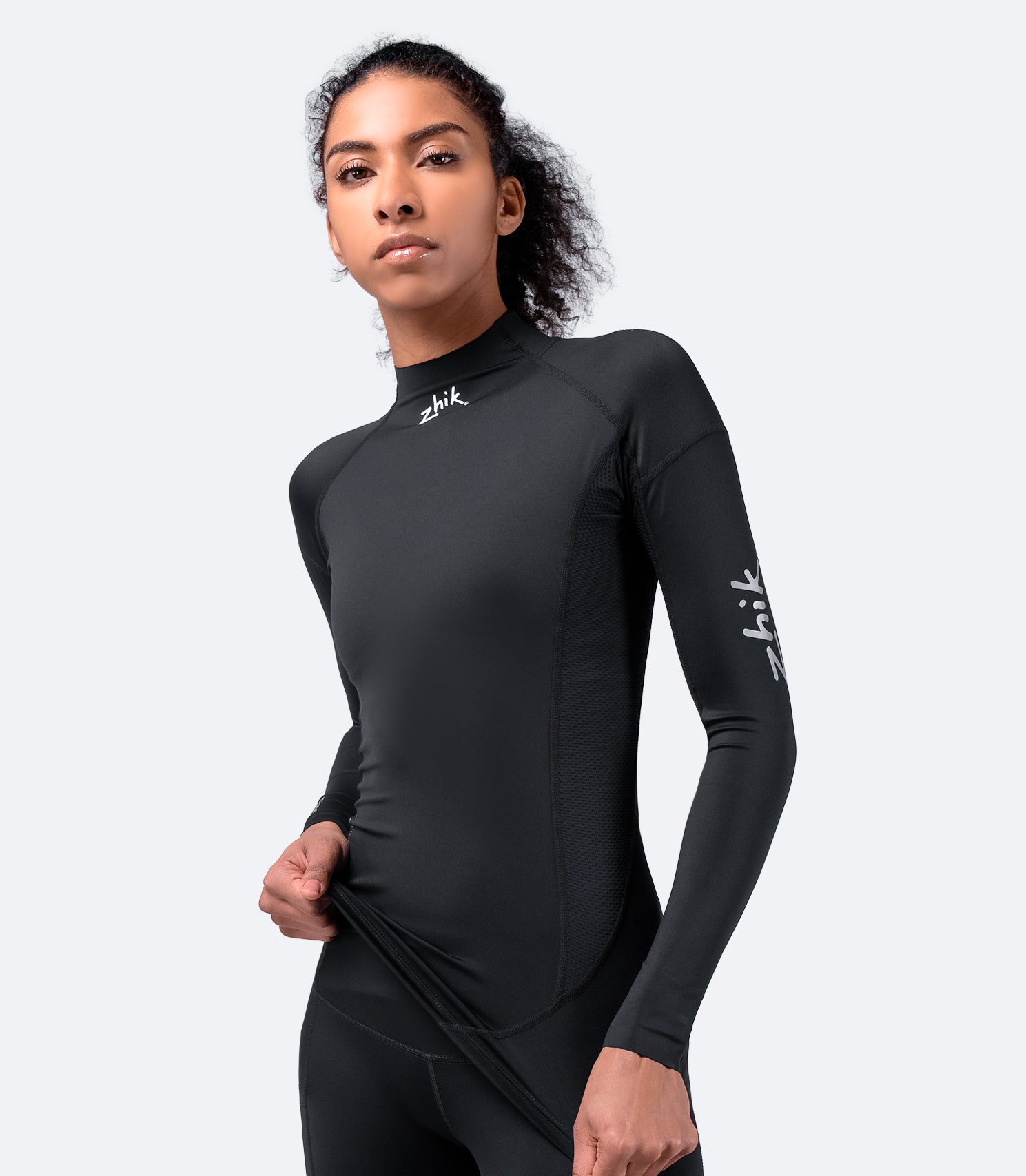Front view of Zhik Women's Black Eco Spandex Long Sleeve Top with breathable perforated side panels and 240GSM fabric for durability.