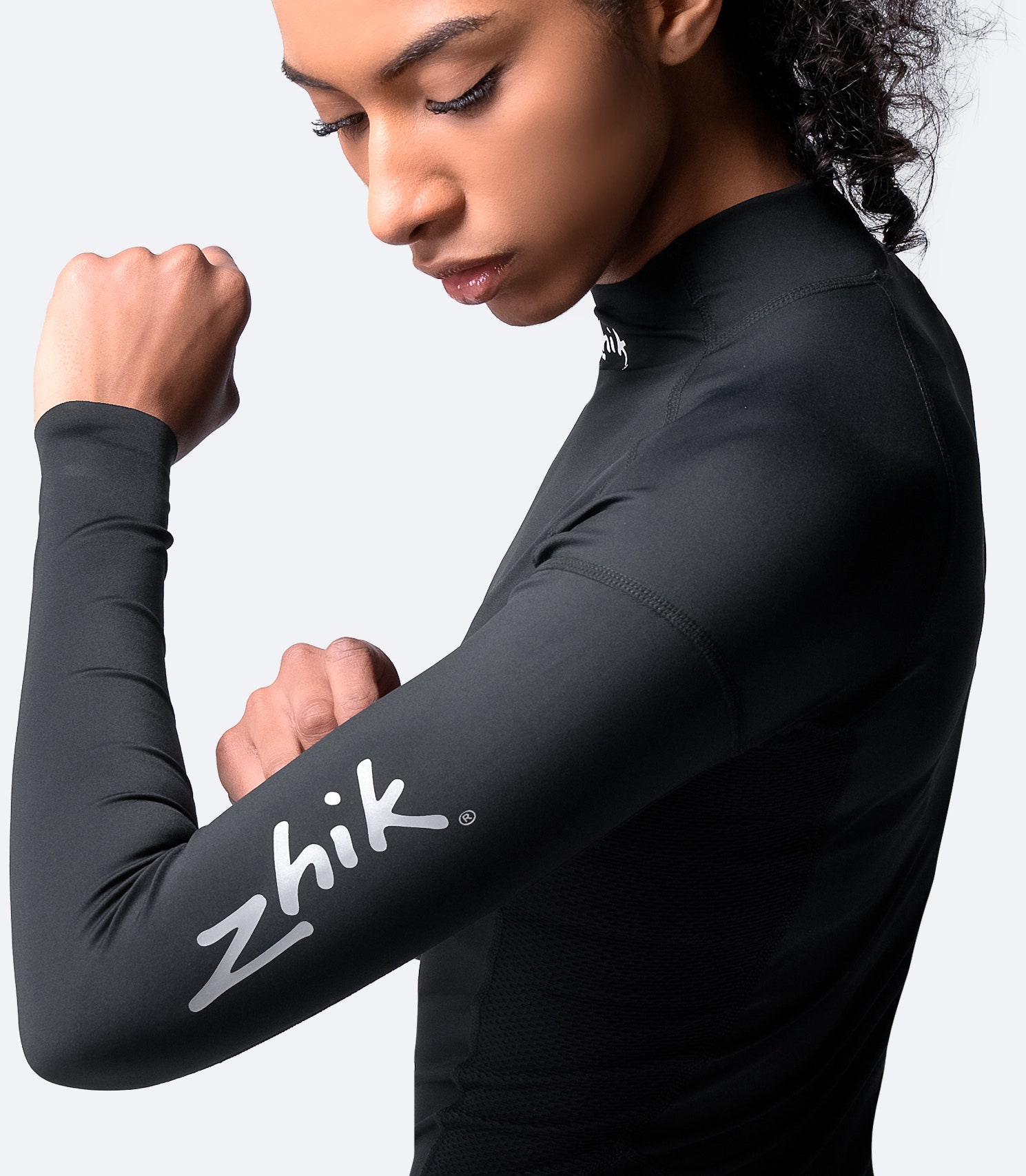Side view of Zhik Women's Black Eco Spandex Long Sleeve Top, with visible Zhik logo and high-stretch fabric for optimal movement.