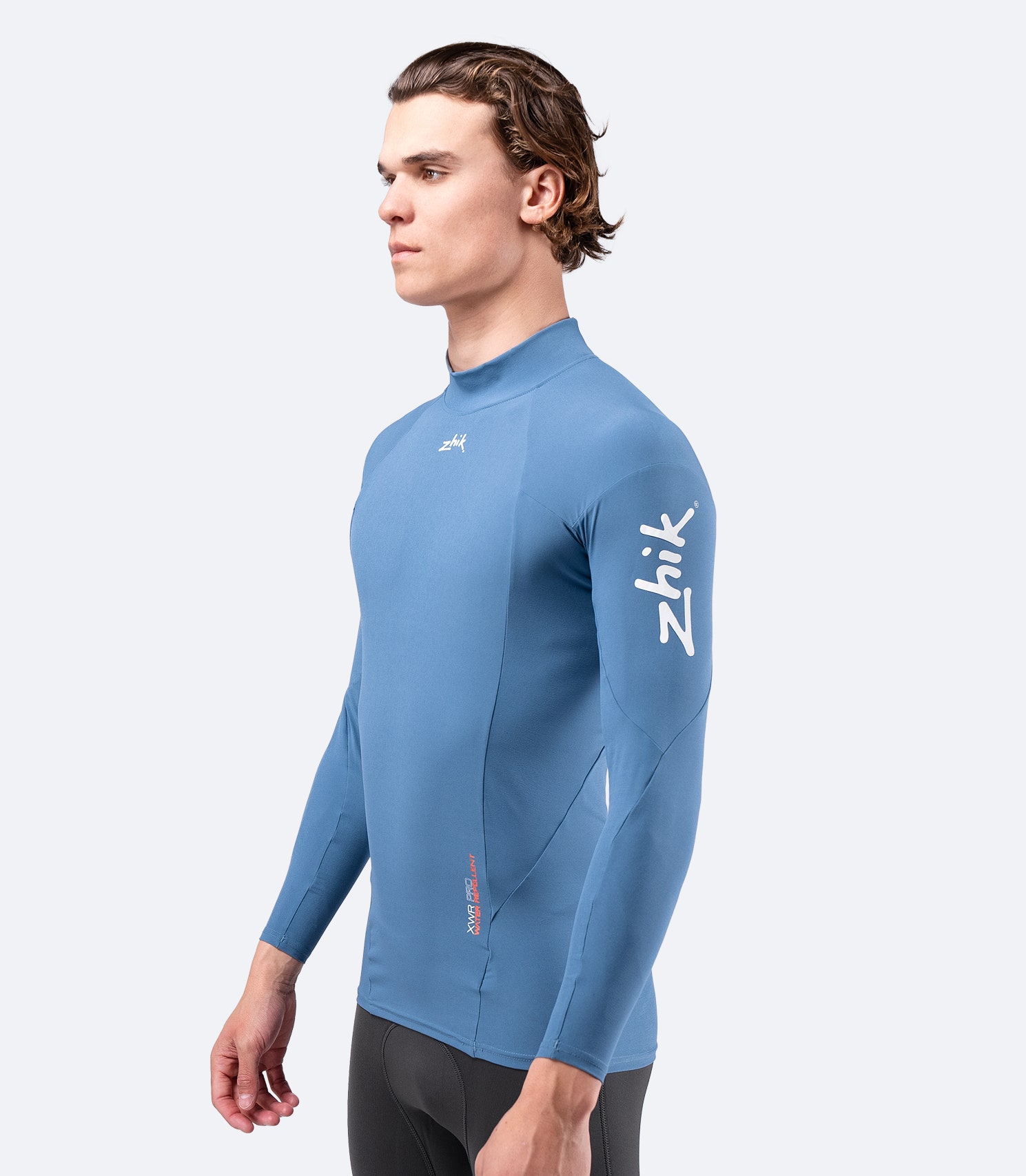 Side view of Zhik Men's XWR Pro Long Sleeve Top in deep blue, featuring a high collar and water-repellent stretch fabric.