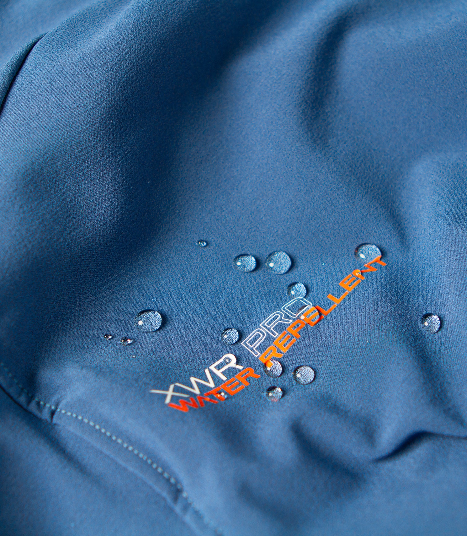 Water beading off Zhik Women's XWR Pro Long Sleeve Top in deep blue, showcasing advanced water-repellent technology.