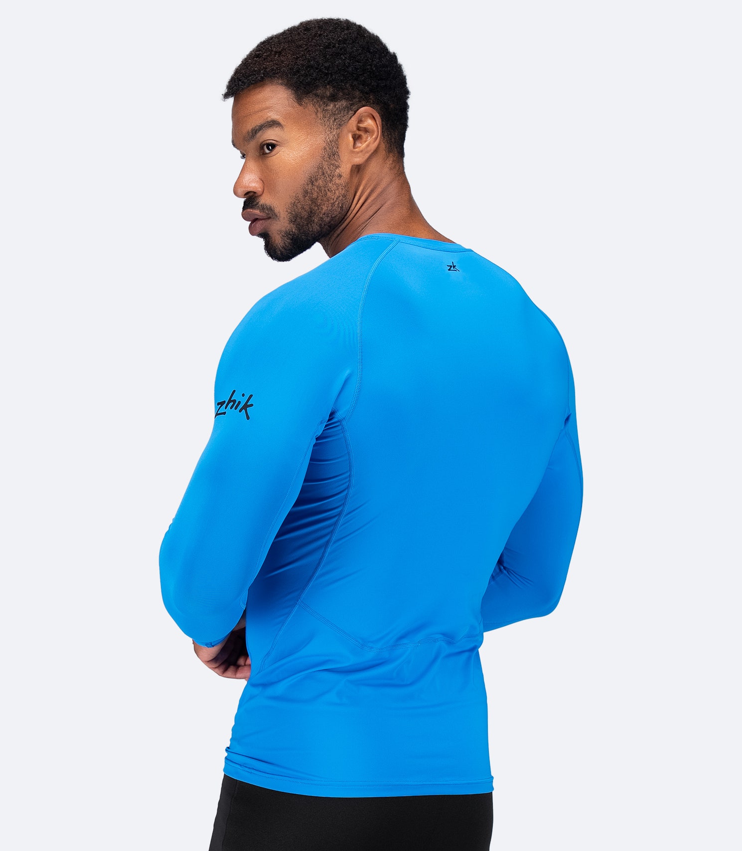 Back view of Zhik Men's Eco Spandex LT Top in Cyan, showcasing breathable stretch fabric and flatlock stitching for anti-rash comfort.