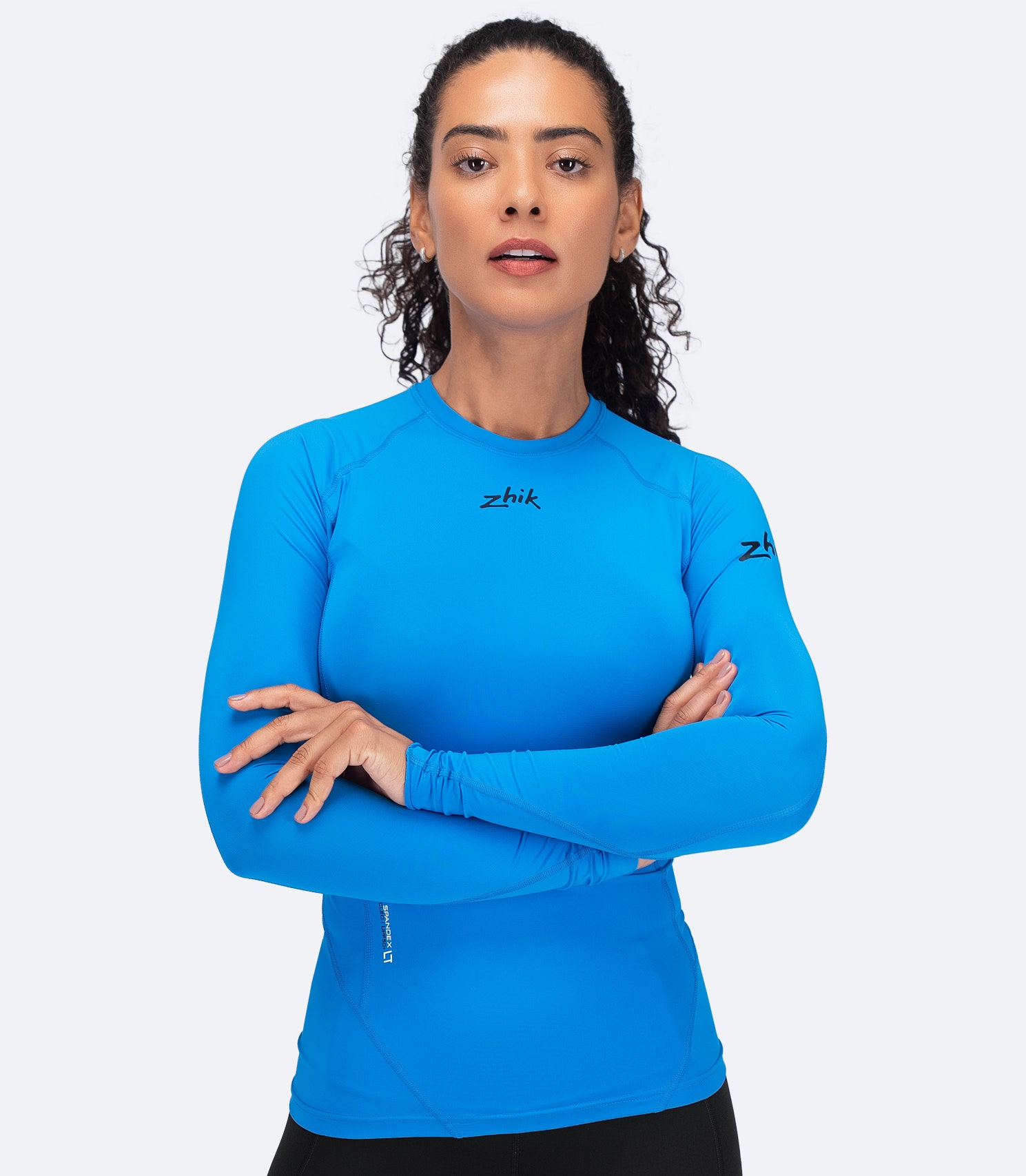 Zhik Women's Eco Spandex LT Top in Cyan with arms folded, showing flexible fit and flatlock seams for comfort.