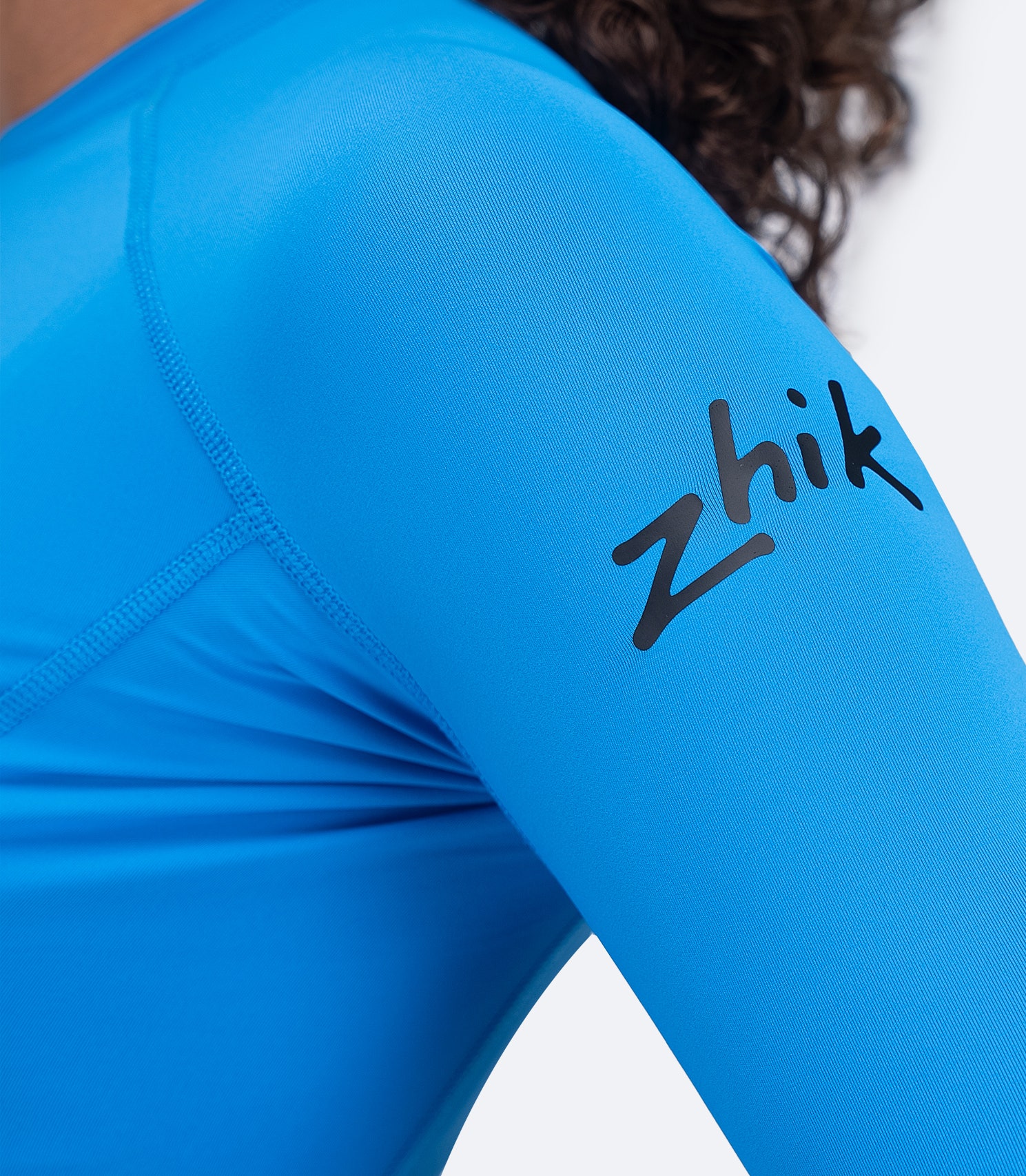 Close-up of side arm on Zhik Women's Eco Spandex LT Top in Cyan with visible Zhik logo and ultra-light fabric.