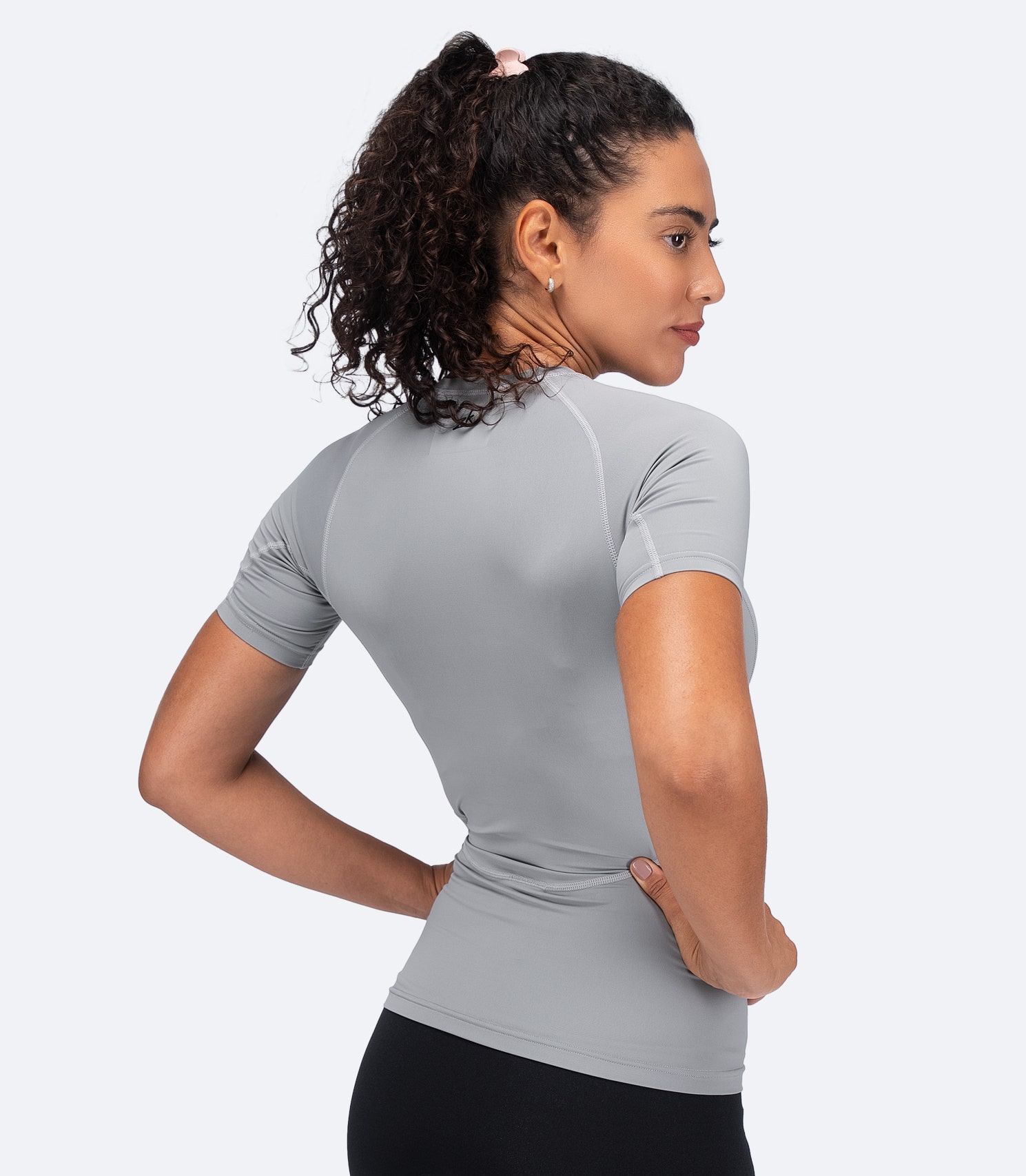 Back view of Zhik Women's Eco Spandex LT Top in Platinum with hands on hips, featuring ergonomic seams and anti-rash stitching.