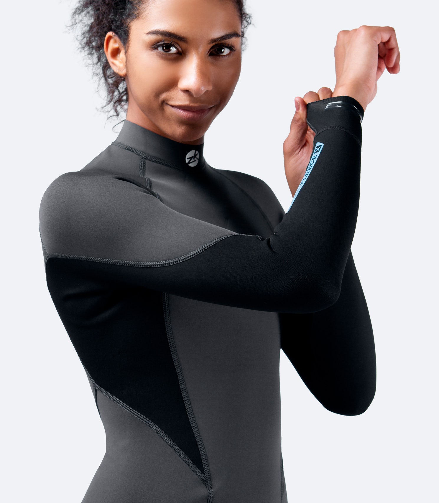Close-up of Women's Zhik Microfleece™ X Top in black, wrists raised, showcasing 4-way super-stretch neoprene flexibility and durable construction.