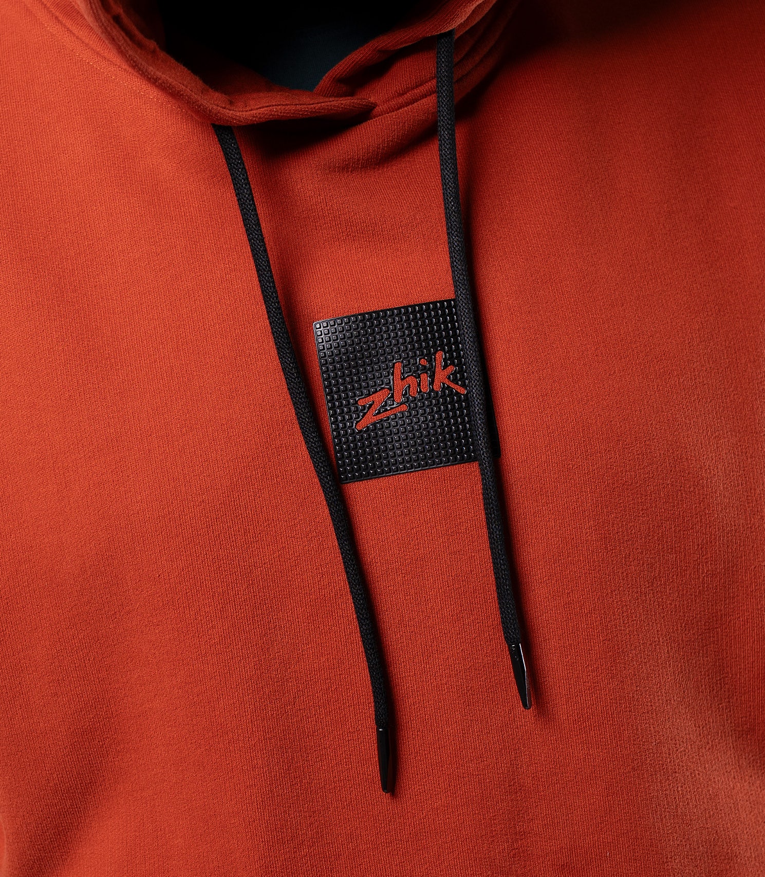 Close-up of textured Zhik logo on Red Earth Men's Carbon Hoodie, subtle branding on premium cotton