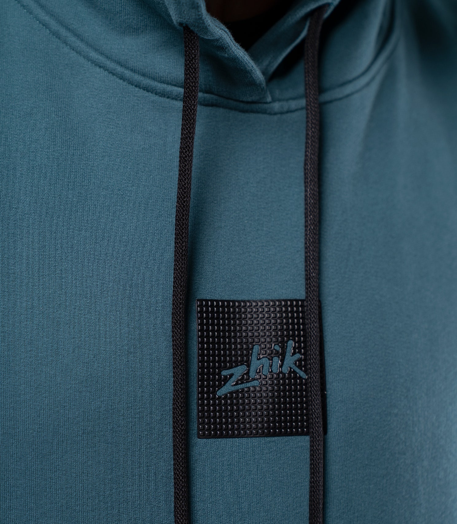 Close-up of textured Zhik logo on Deep Teal Men's Carbon Hoodie, subtle branding on midweight cotton