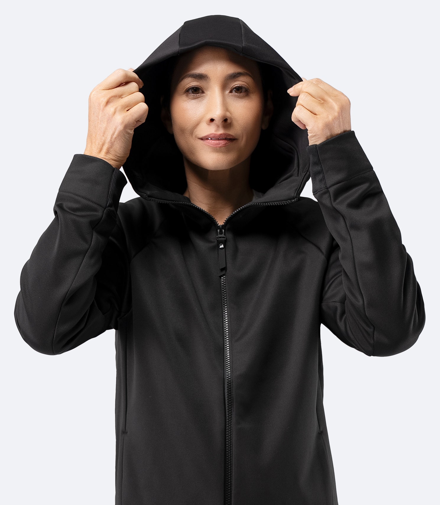 Model adjusting hood on Zhik Women’s Thermo TechFleece Hooded Jacket in black