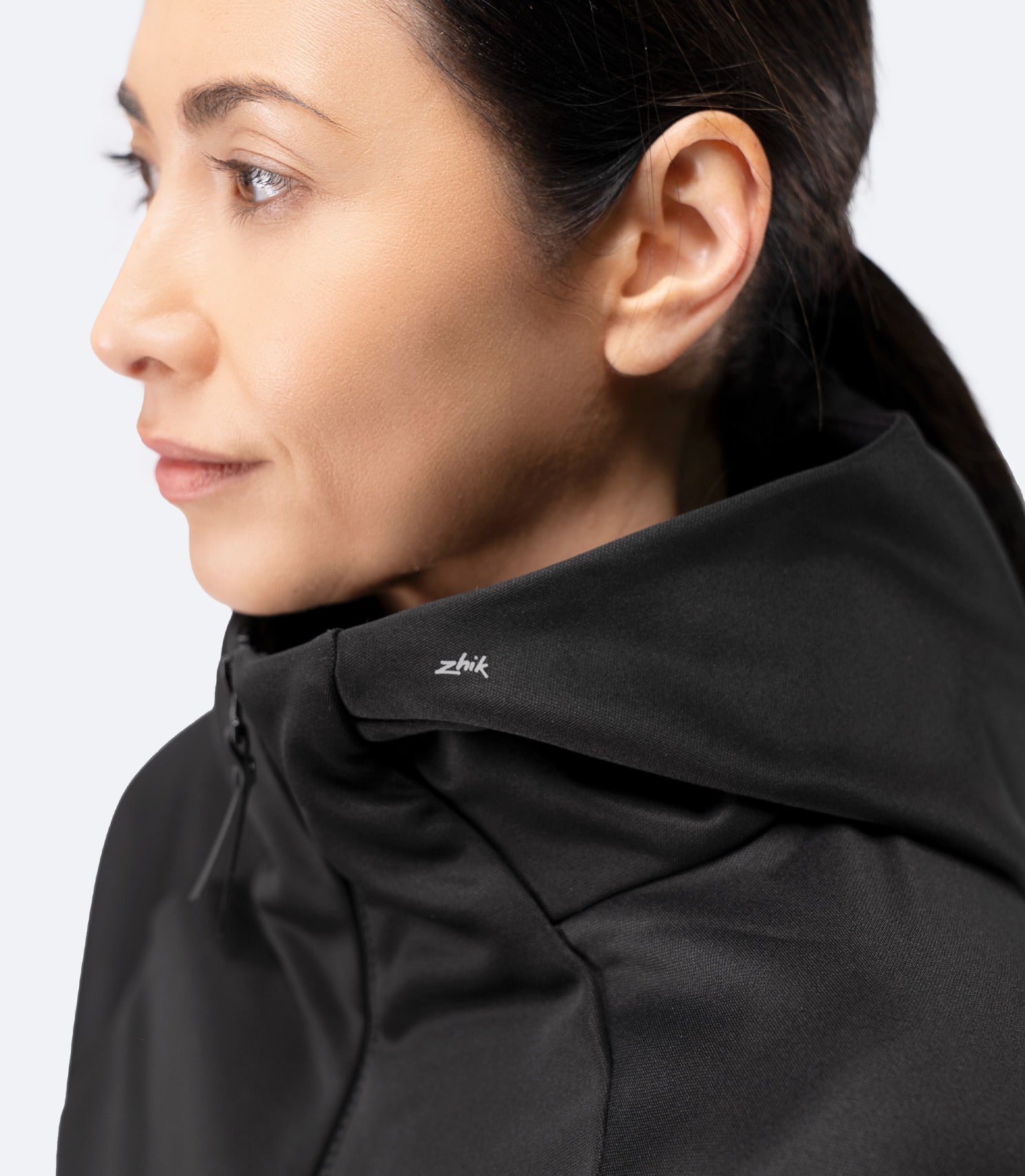 Side profile of Zhik Women’s Thermo TechFleece Hooded Jacket in black with hood up