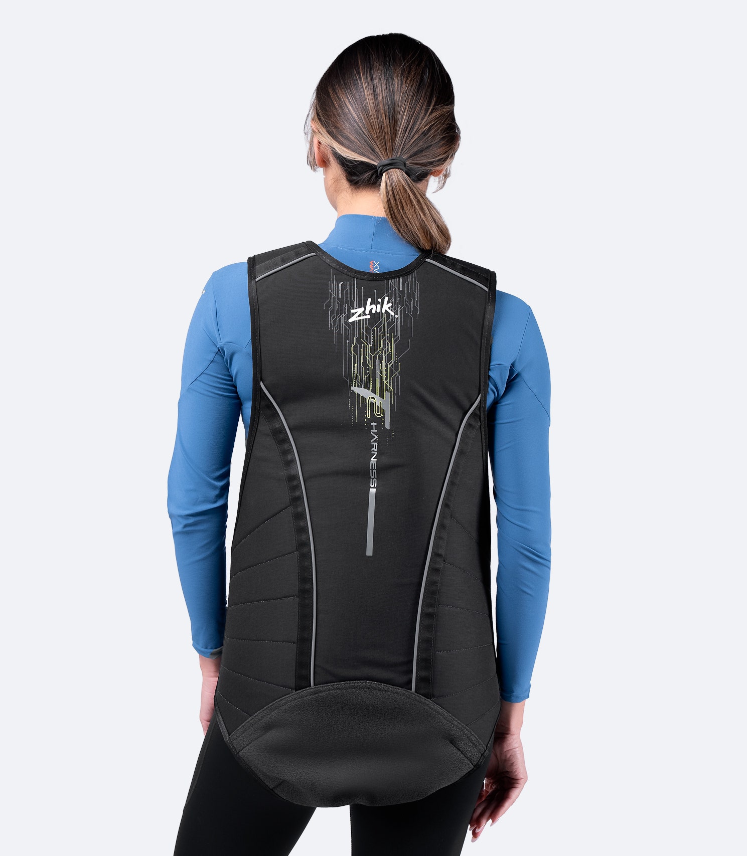 Female sailor in black Zhik T2 Trapeze Harness, rear view showing durable Kevlar seat reinforcement and ergonomic fit.