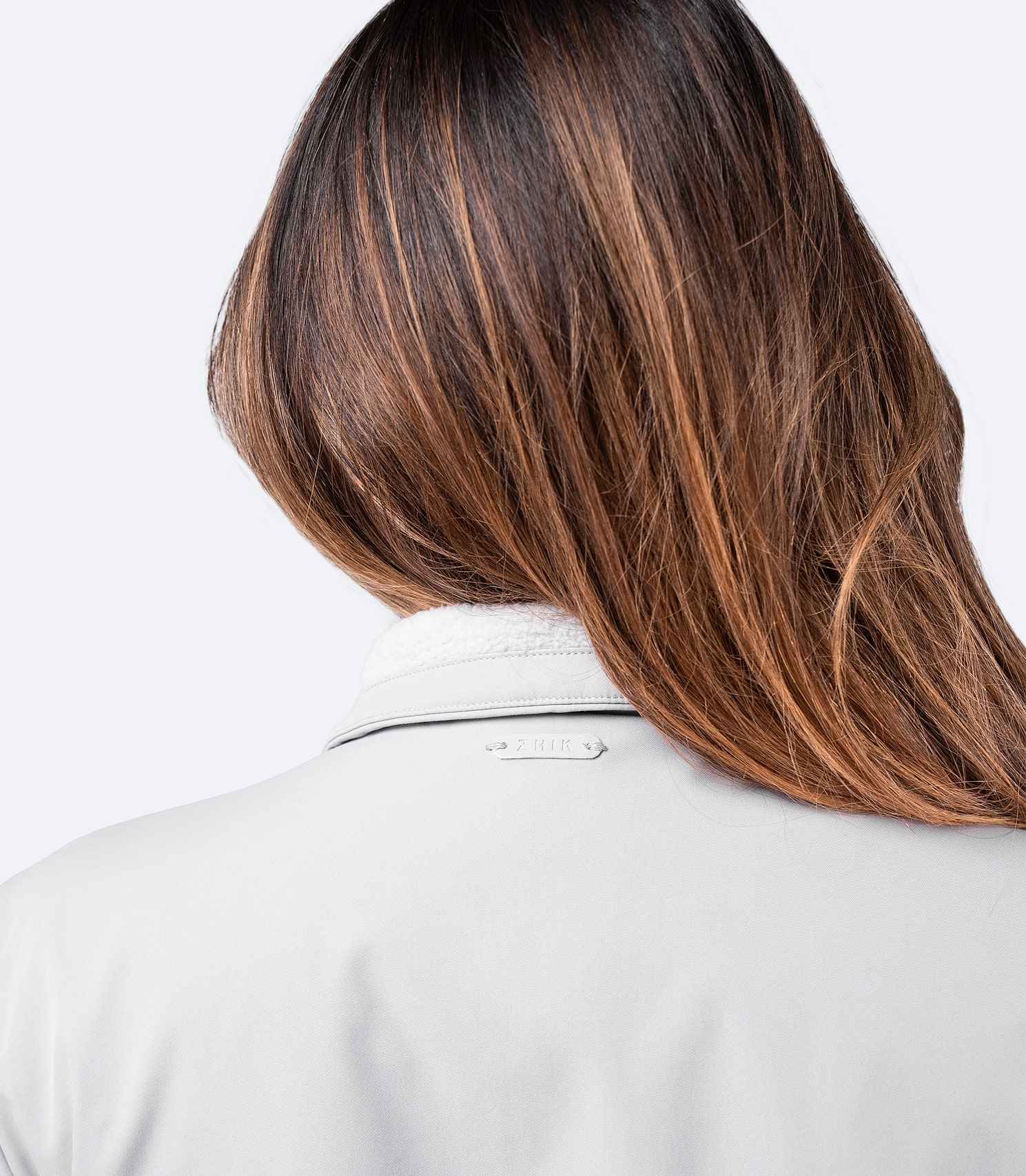 Close-up of the rear neck and shoulder of platinum Women's Flight Jacket, featuring the Zhik logo just below the collar.