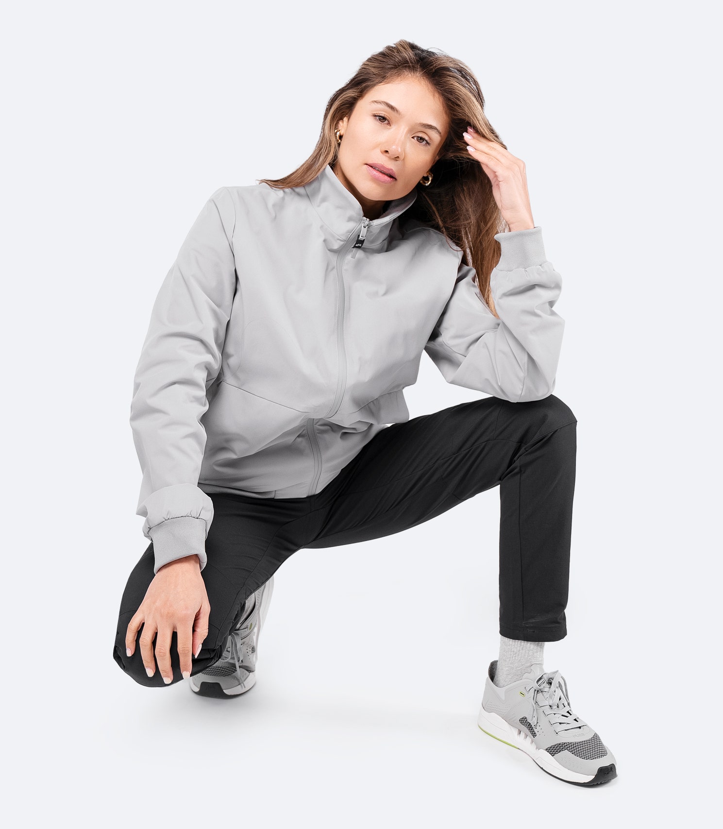 Front view of platinum Women's Flight Jacket zipped up, worn casually while squatting, showcasing its relaxed fit and fleece-lined collar.