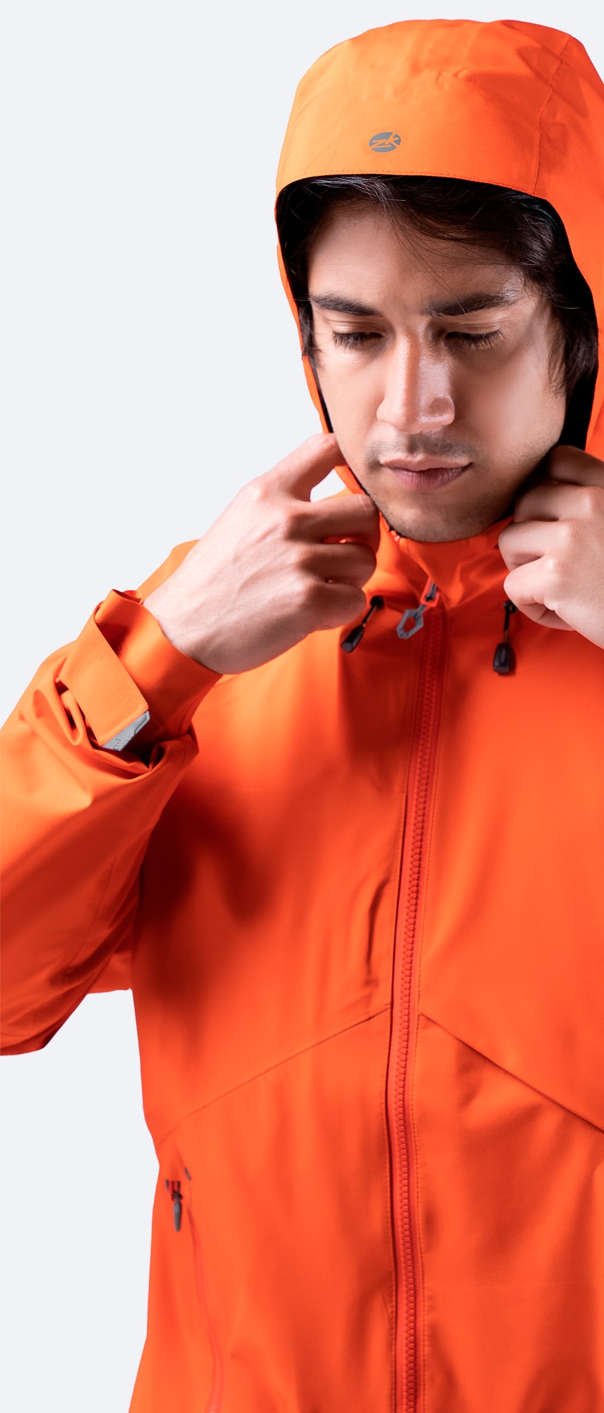 Zhik Men's Flame Red INS200 Jacket with hood up, hands adjusting the fit, showcasing waterproof fabric and adjustable cuffs for protection