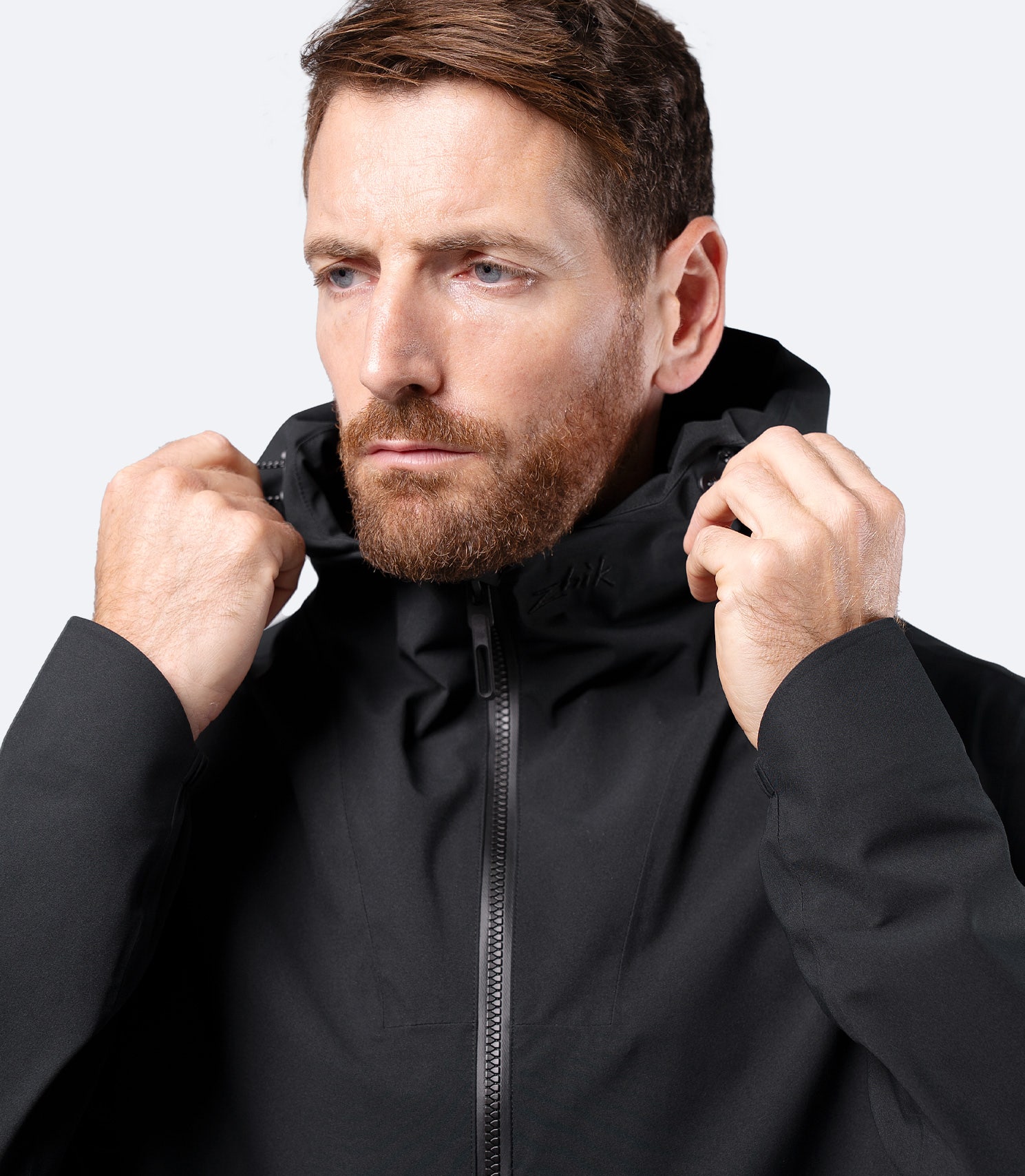 Close-up of hood-down collar on Zhik Men's Black INS300 Jacket, male model zipped up at the chest
