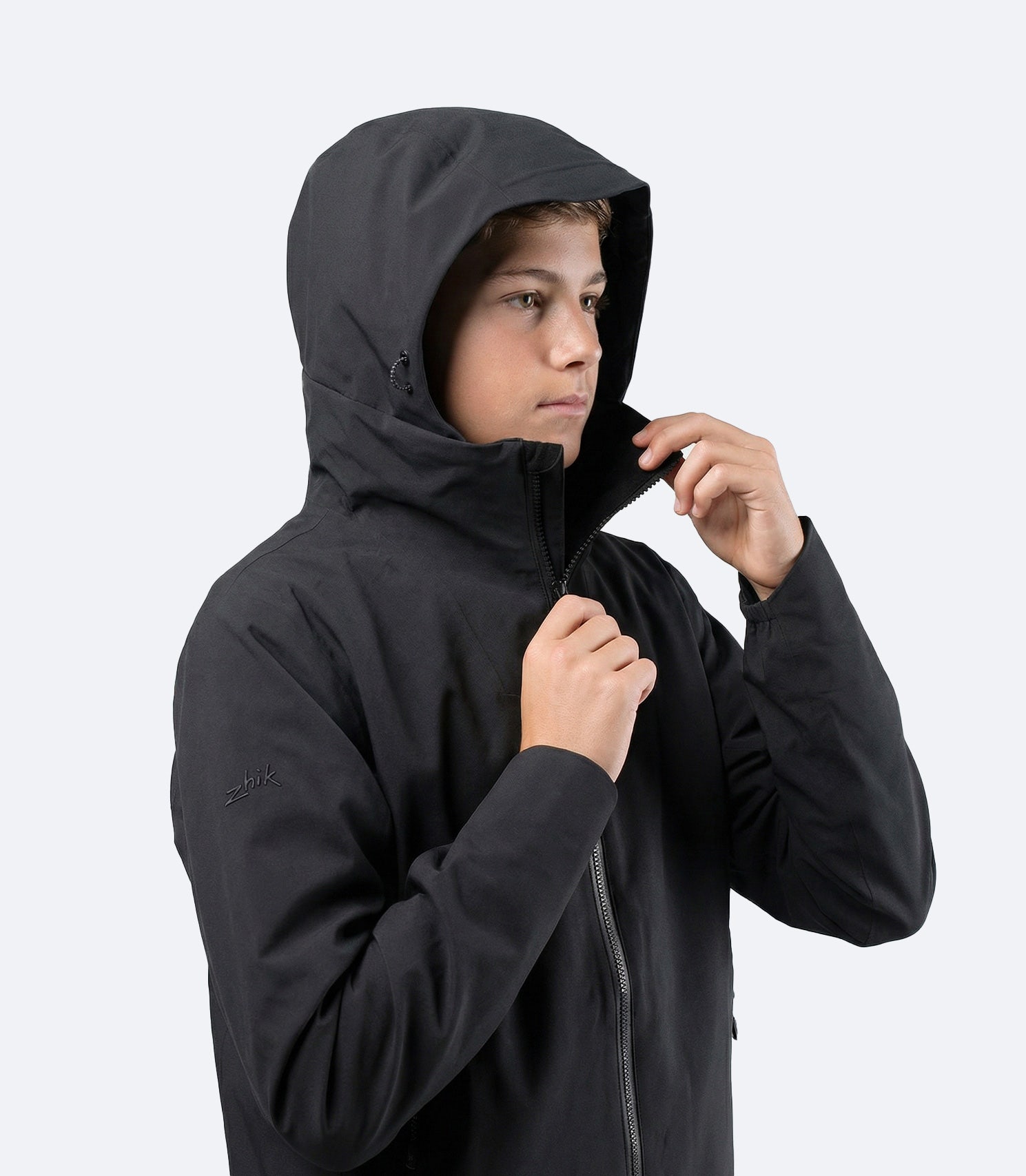 Side view of Zhik Youth INS300 Inshore Active Jacket in black with hood up for wet, windy inshore conditions