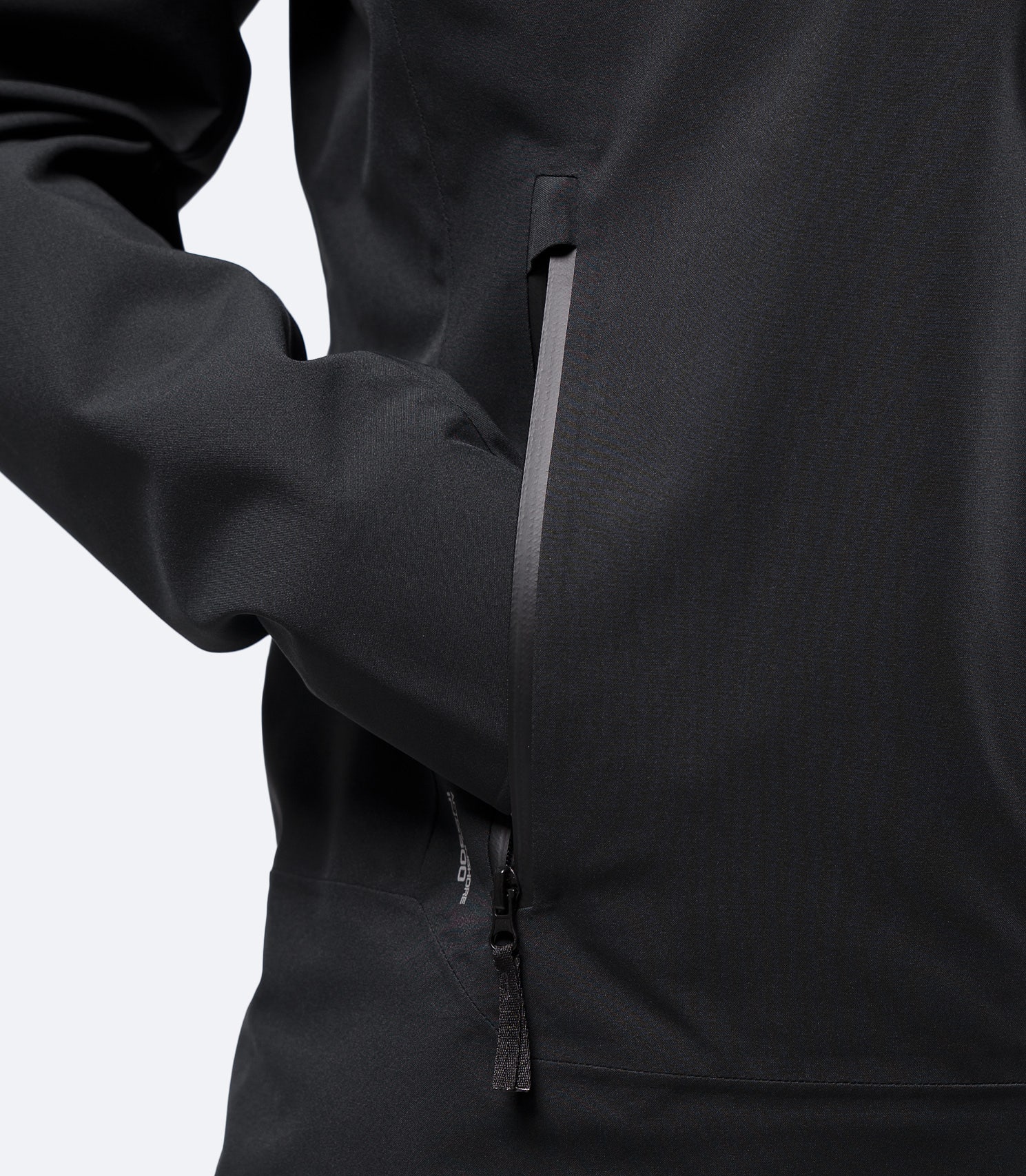 Closeup of hand in zip pocket on Zhik Youth INS300 Inshore Active Jacket in black, showing water resistant zipper