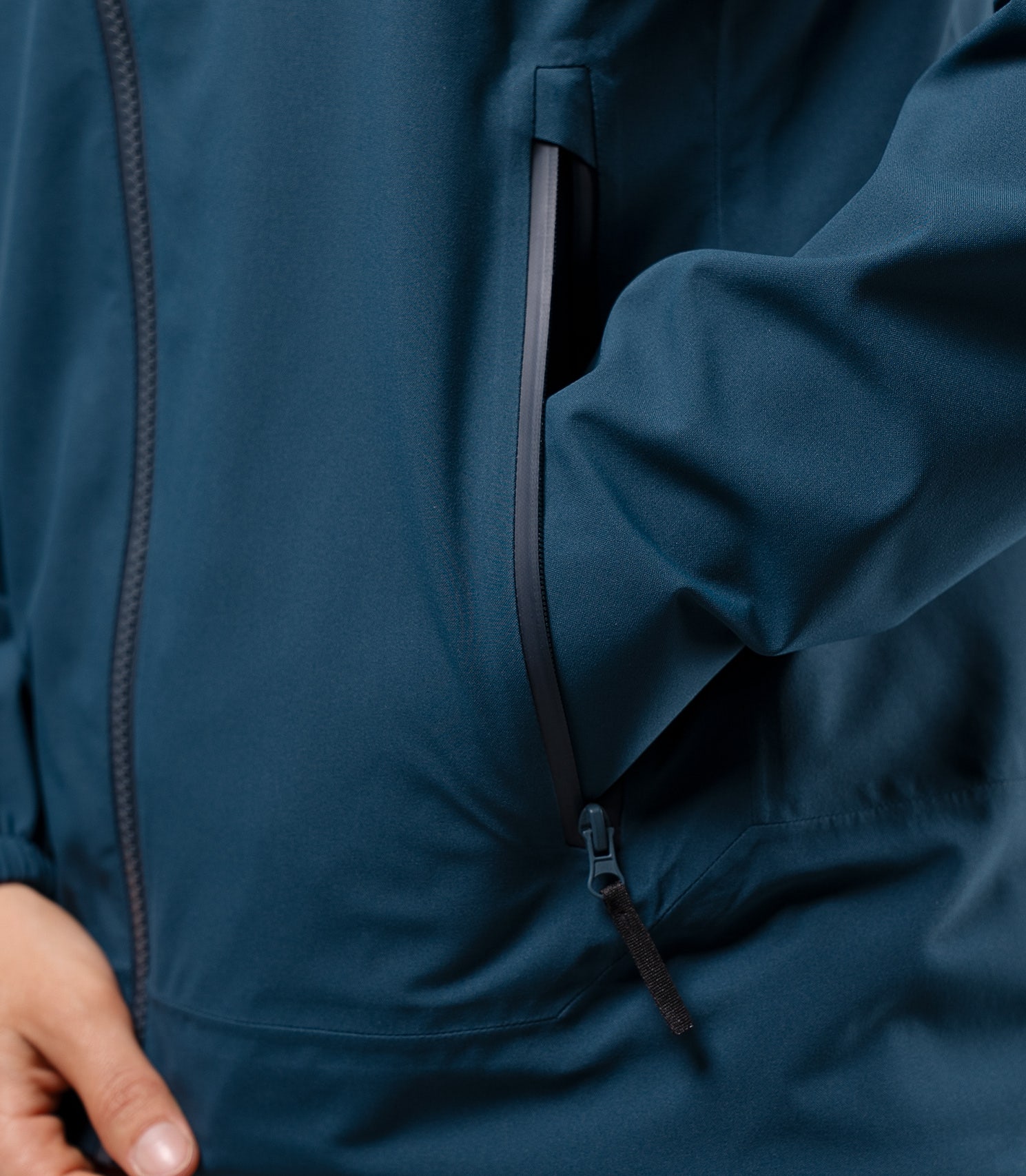 Close-up of hand in front pocket of Zhik INS300 Women's Inshore Active Jacket in Deep Teal, showing oversized zip pocket