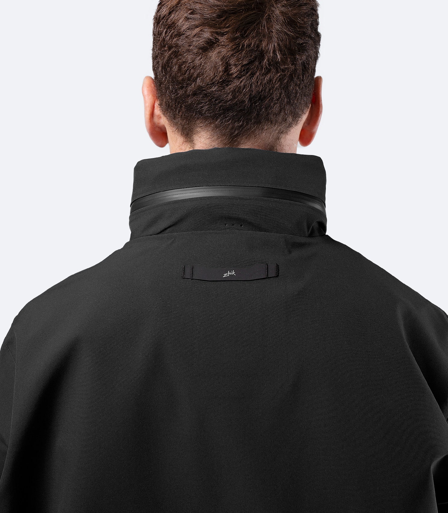 Close-up of packed hood stowed at rear on Zhik Men's Black INS400 inshore jacket with zip compartment