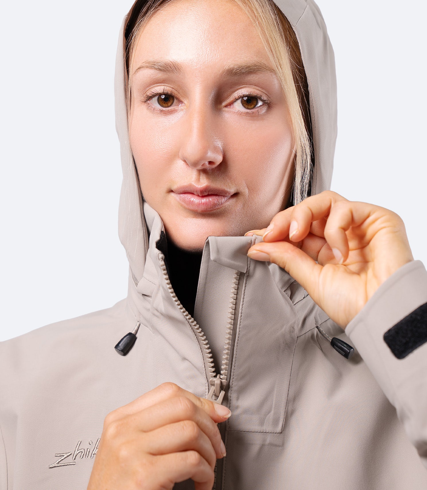 Close-up front of Zhik Women's INS400 Jacket in stone, hood up, highlighting thermal-lined collar and upper zip seal