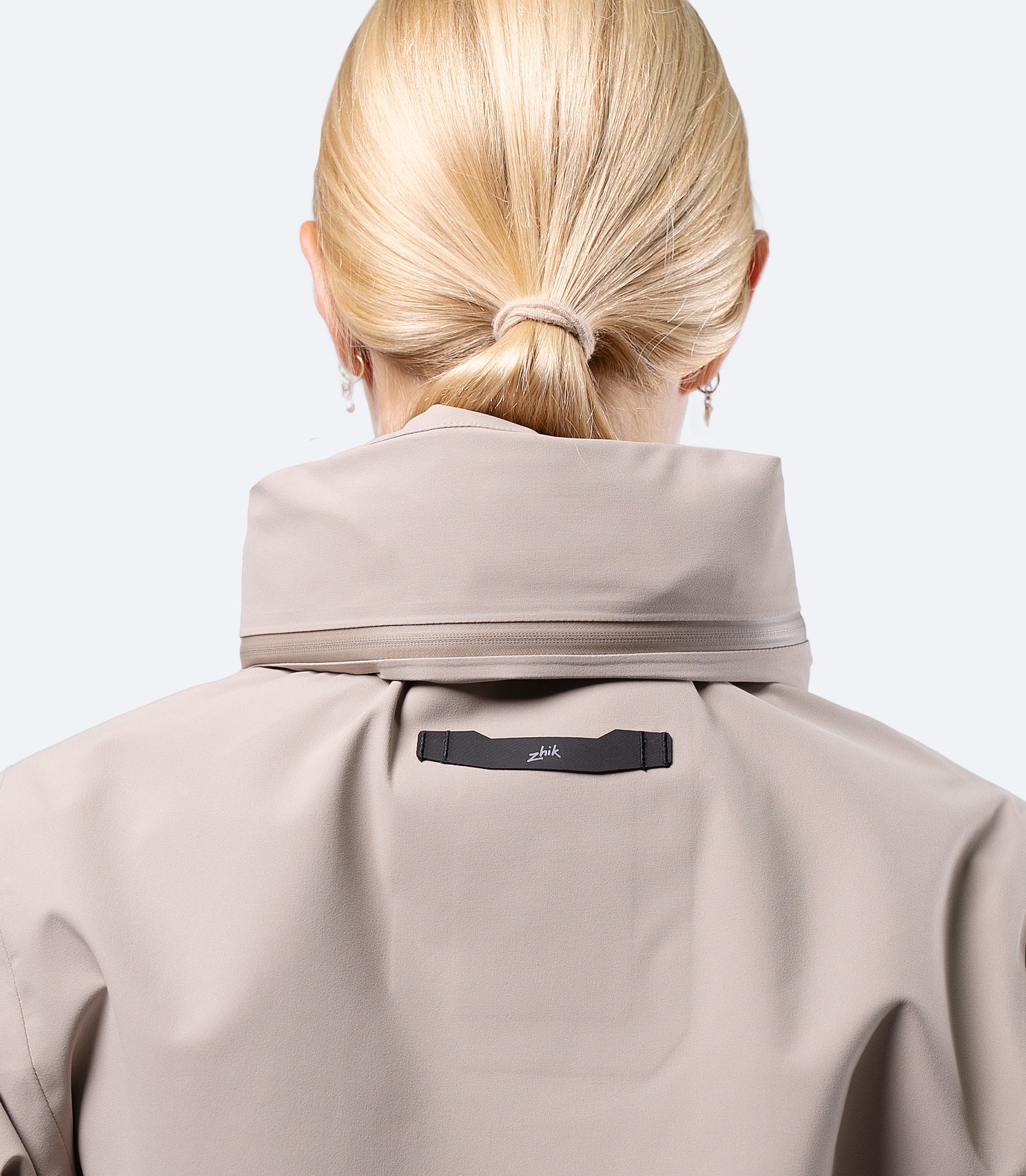 Zhik Women's INS400 jacket in Stone, rear hood stowed with low profile zip pocket for packable storage