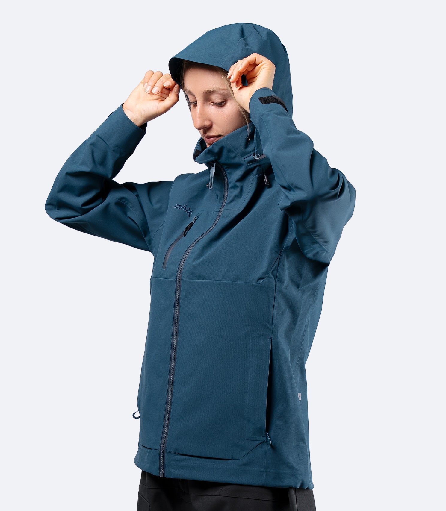Zhik Women's INS400 inshore jacket in Deep Teal on female model, hood up, front view for active sailing