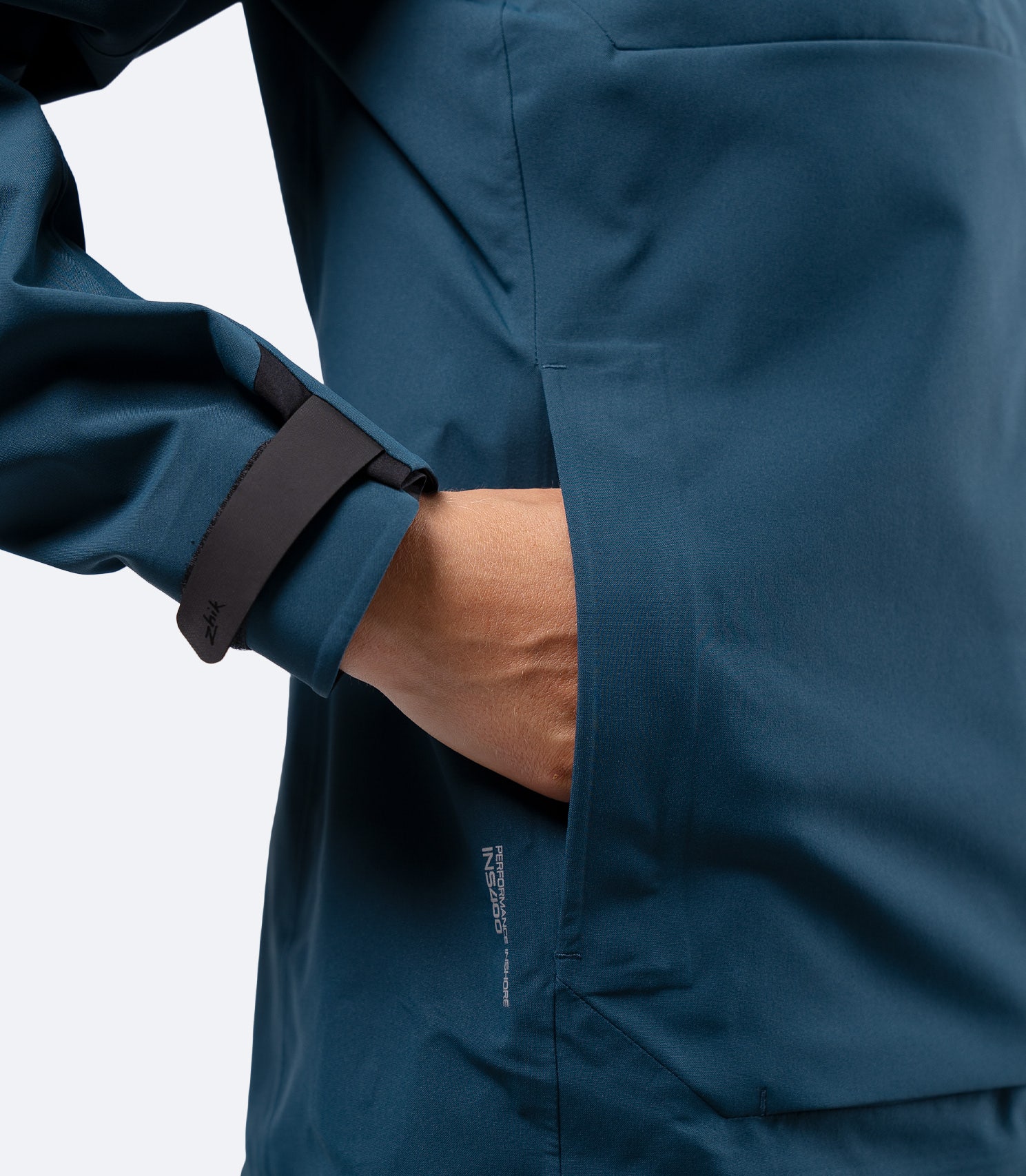 Hand in front pocket of Zhik Women's INS400 jacket in Deep Teal, with water resistant zippered storage