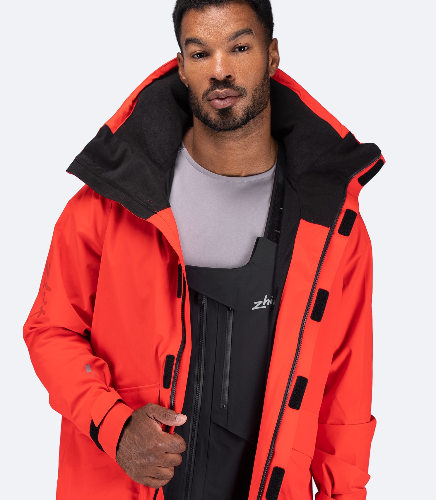 Zhik Men's OFS600 Jacket in flame red with zipper open and hood down, showing breathable mesh core and ergonomic collar.