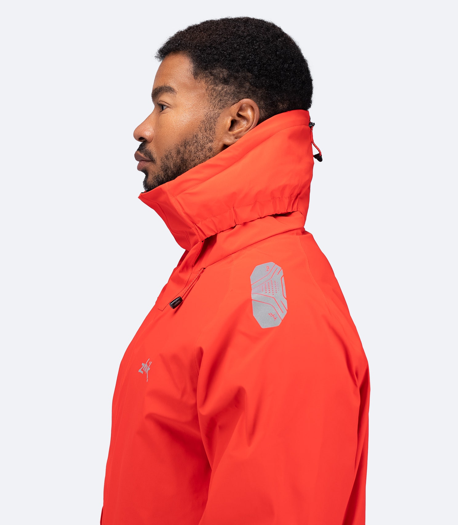 Side view of Zhik Men's OFS600 Jacket in flame red with hood down, showing articulated fit and ergonomic collar design.