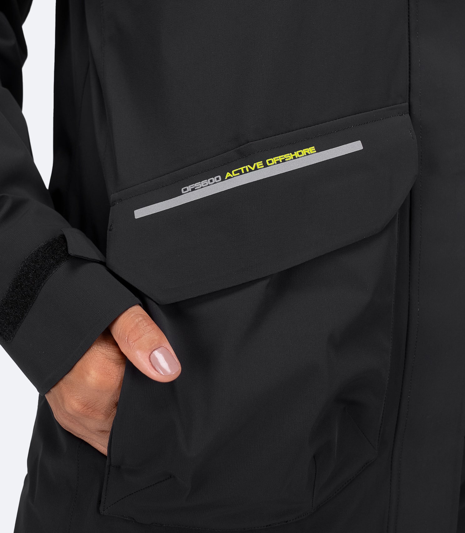 Zhik Women's OFS600 black jacket close-up showing cargo pocket and separate fleece-lined hand warmer.