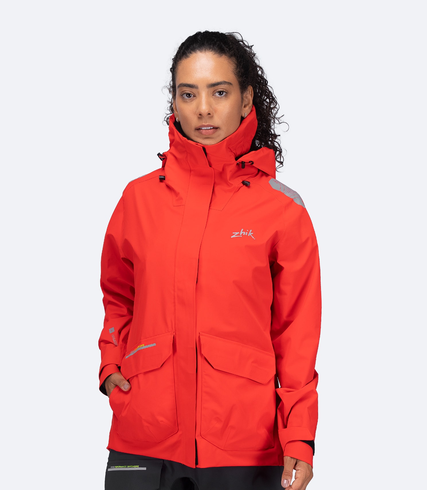 Zhik Women's OFS600 Offshore Jacket in flame red, front view with storm collar raised and hood stowed.