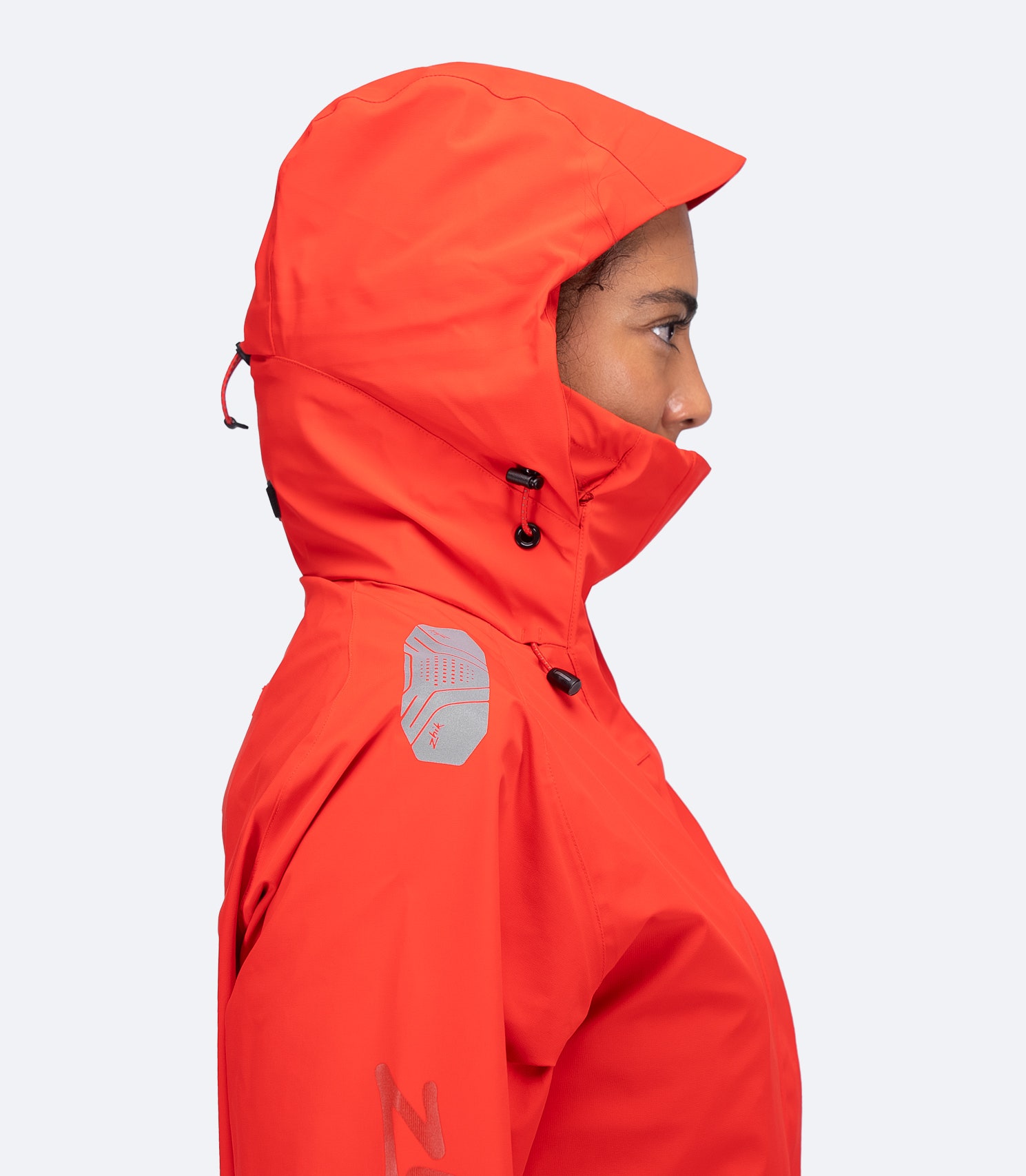 Zhik Women's OFS600 Jacket in flame red, side view with hood up and reflective laser-cut detail on shoulder.