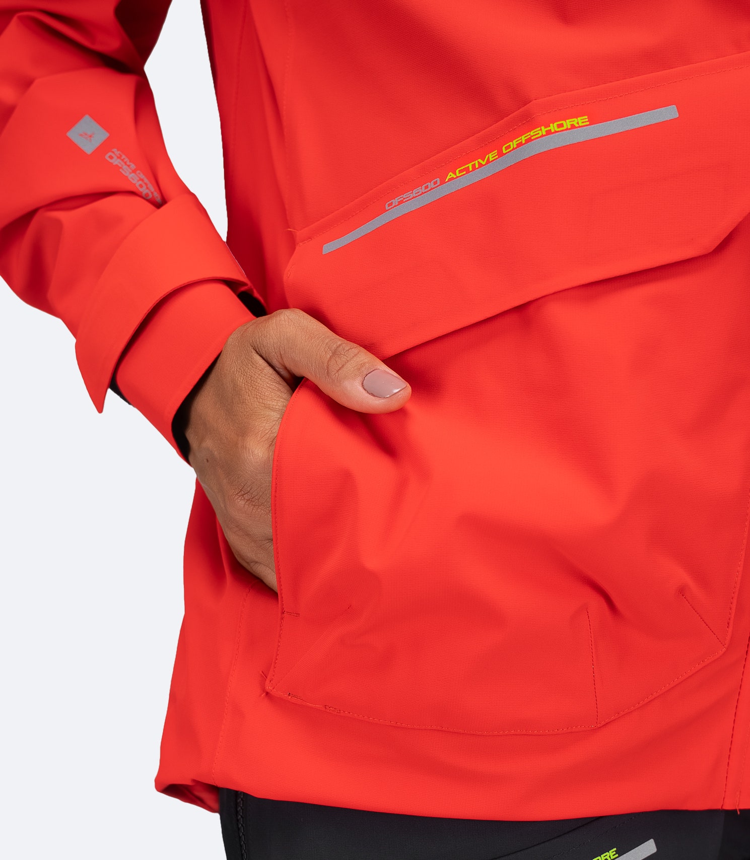 Zhik Women's OFS600 Offshore Jacket in flame red, showing dual cargo pocket with separate fleece-lined hand warmer section.