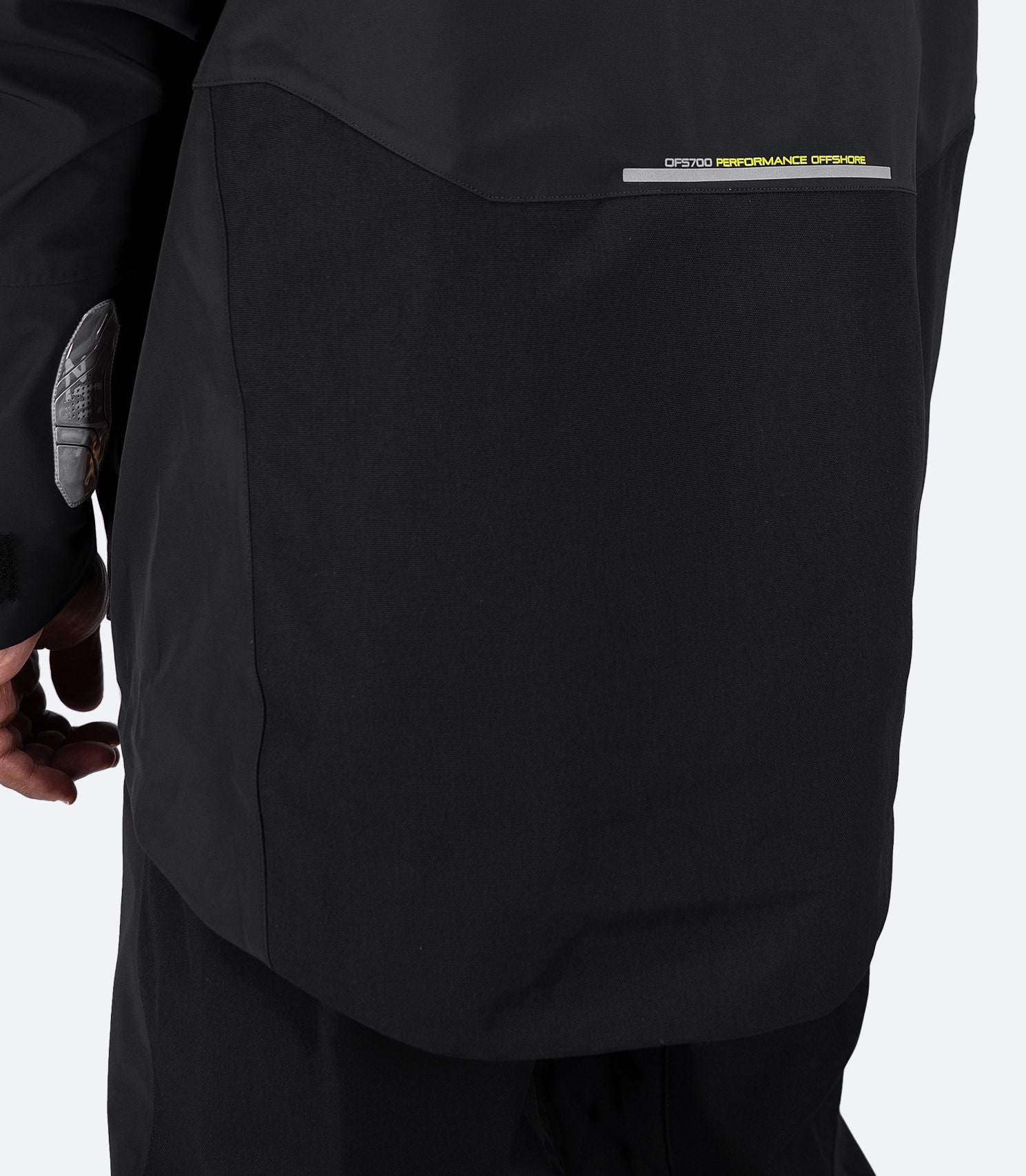 Close-up of lower back on black Zhik OFS700 Jacket showing reinforced 450D seat panel and seam-taped construction for durability.